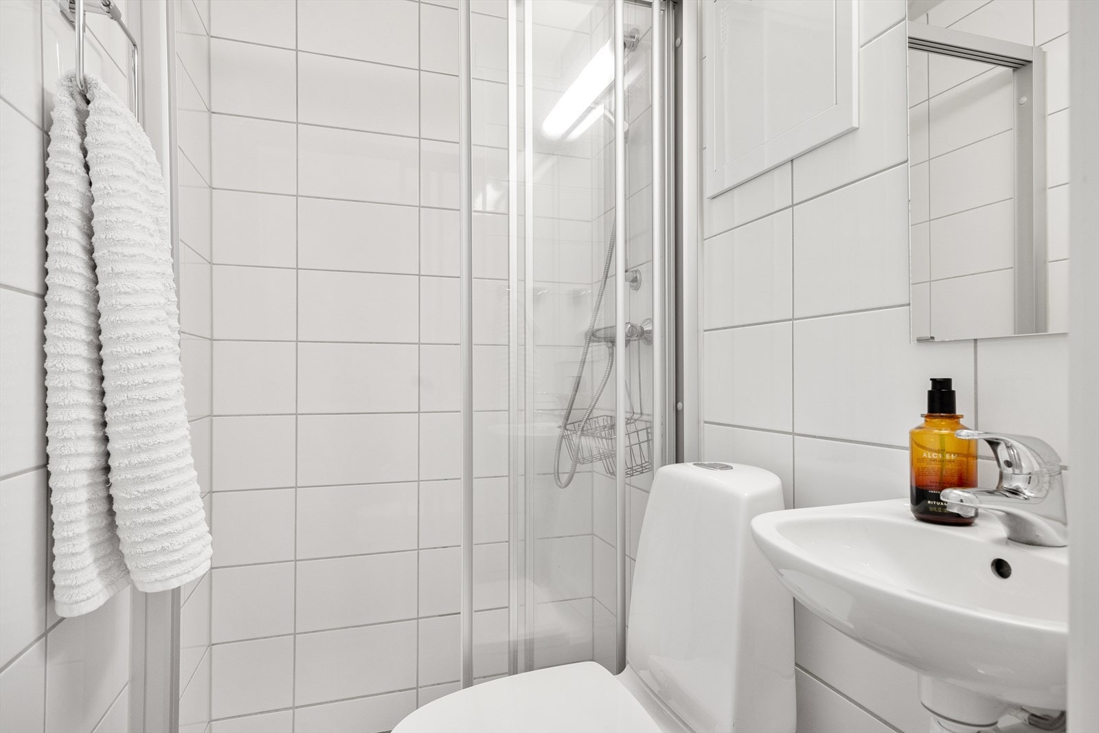 Flislagt gulv med gulvvarme og flislagte vegger. Dusjnisje med skyvedører i glass og gulvstående toalett fra IFØ. Galleribilde