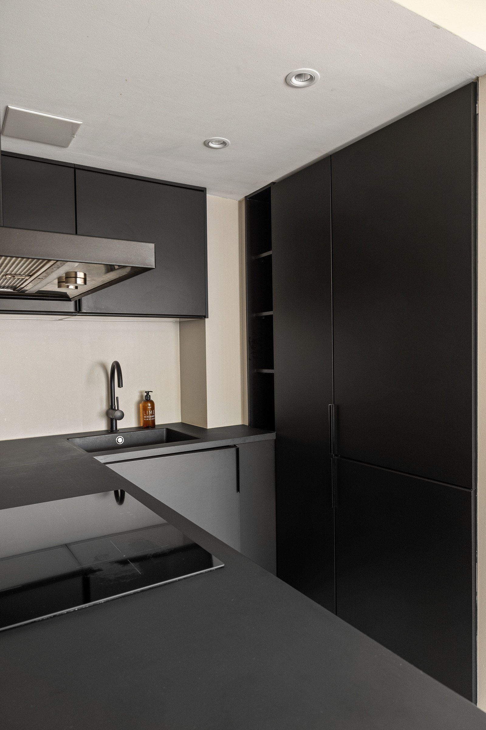 Kjøkkenet eer innredet med integrerte hvitevarer som komfyr, induksjonstopp, smal oppvaskmaskin og kjøl-/fryseskap. Galleribilde