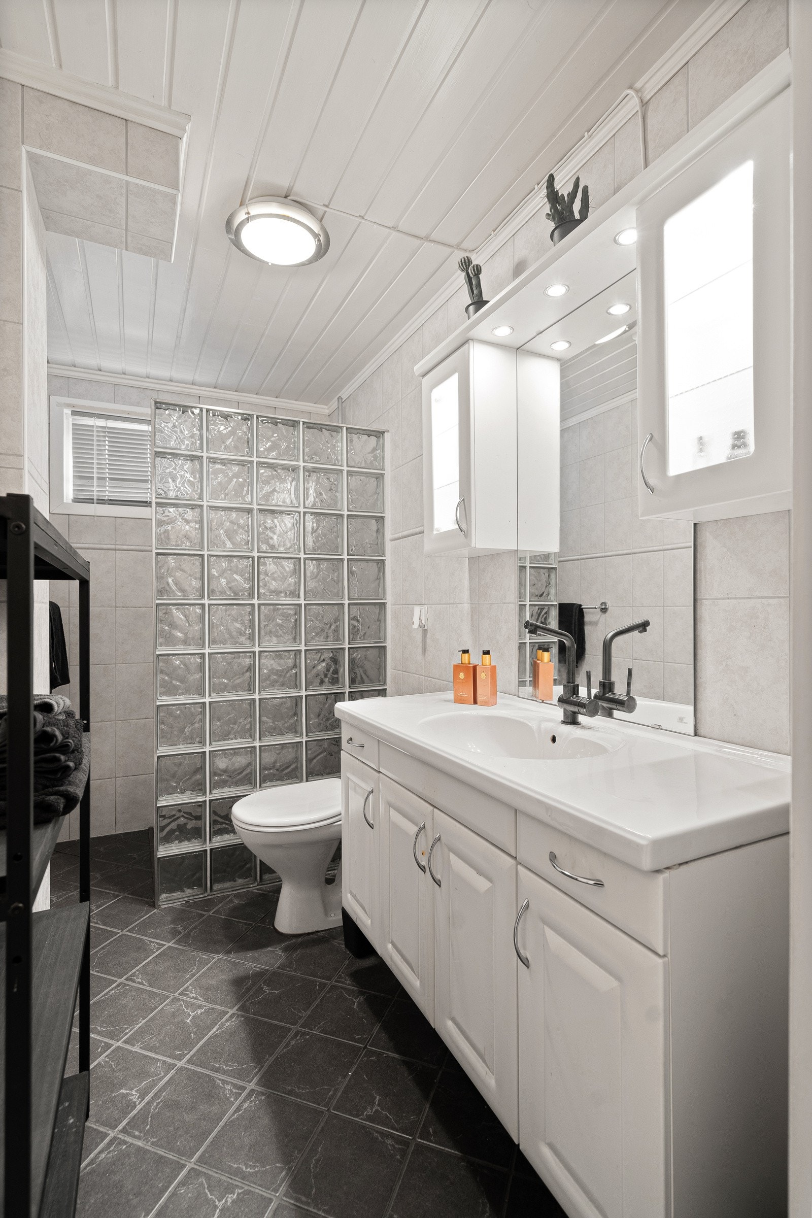 Badet har dusjsone, servant med innredning og toalett Galleribilde