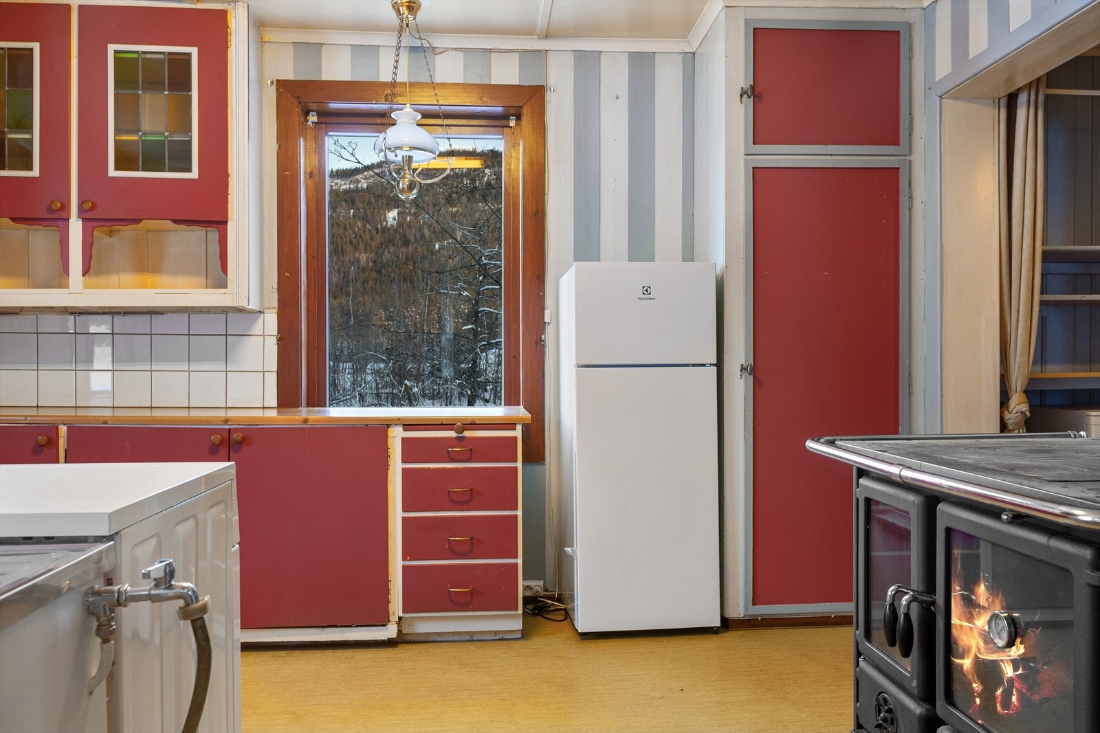 Frittstående kjøleskap og komfyr, samt opplegg til vaskemaskin. Galleribilde