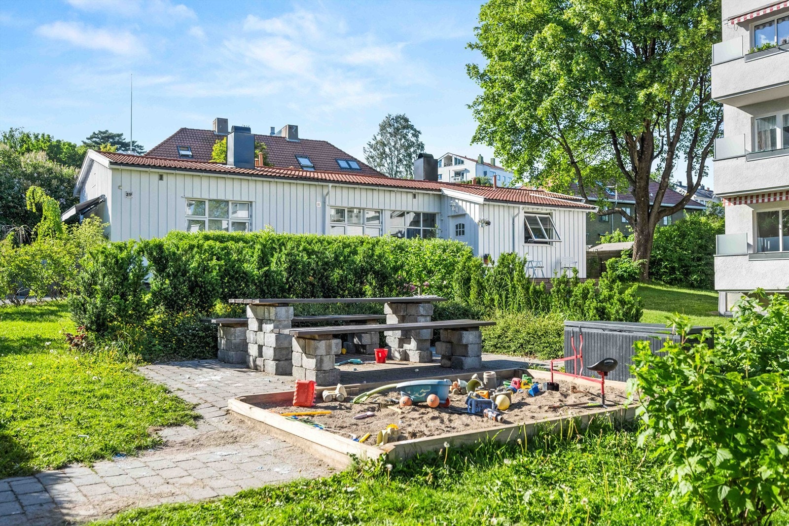 Felles tomt for borettslaget opparbeidet med plenarealer, diverse beplantning, prydbusker, sittegrupper og lekeapparater. Galleribilde