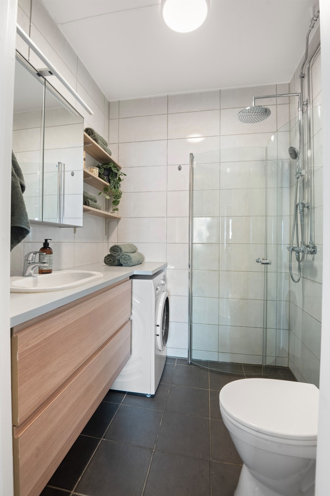 Innredning med servant og 1-greps blandebatteri, flislagte vegger og malt himling, speil på vegg over servant, samt belysning over servant. Galleribilde