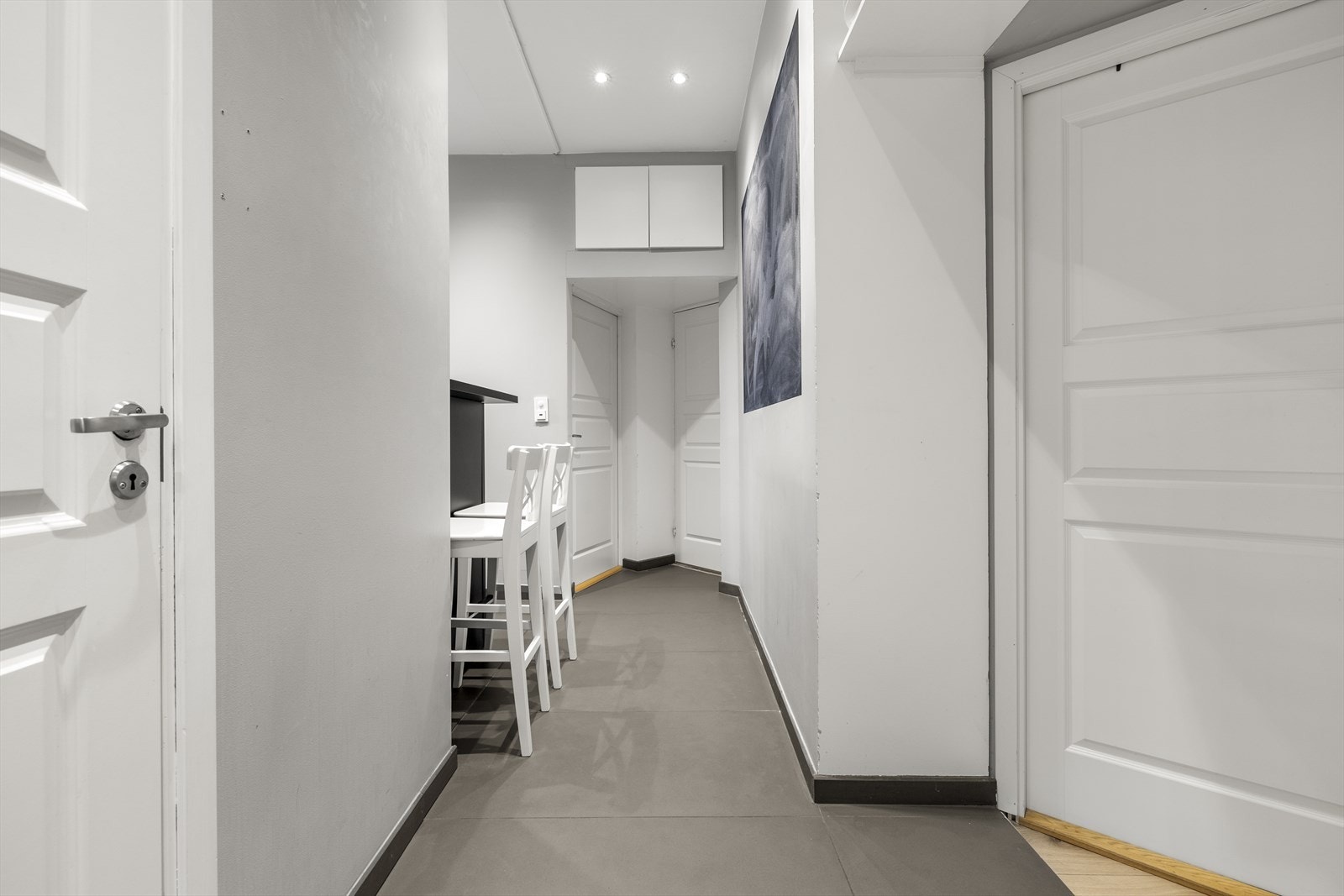 Leiligheten har en innbydende entré med lyse veggflater, store, elegante fliser på gulvet og downlights i taket. Galleribilde