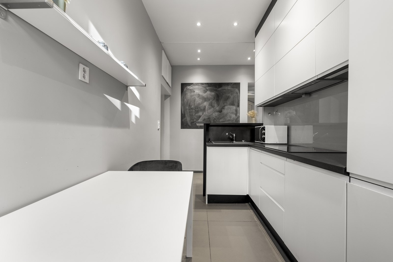 Her finner du integrerte hvitevarer som stekeovn, platetopp, kjøl/frys og kaffemaskin. De samme lyse gulvflisene som i gangen gir et helhetlig preg og gjør rengjøringen enkel. Galleribilde