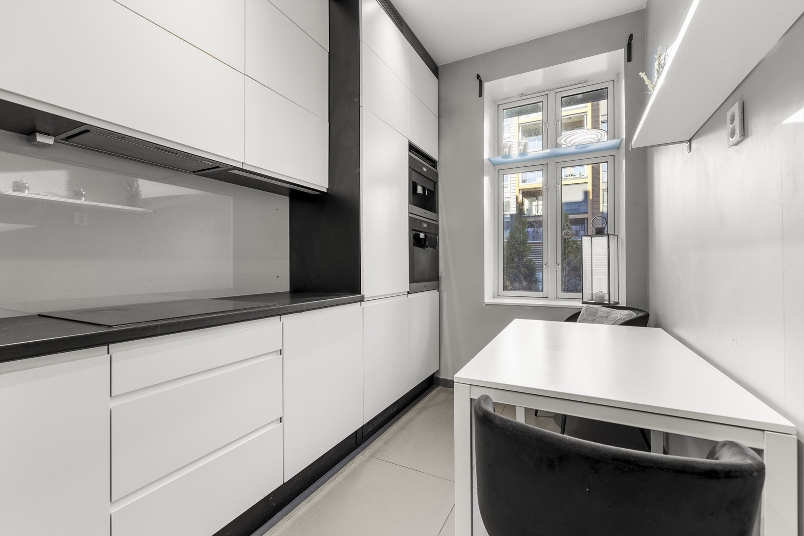 Kjøkkenet har et stilrent uttrykk med lyse, slette fronter, mørk benkeplate og rikelig med både skap- og benkeplass. Galleribilde