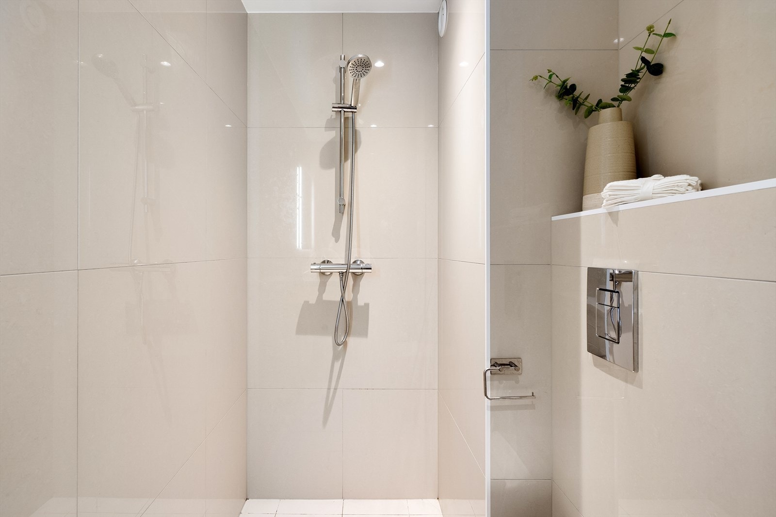 Badet er innredet med vegghengt klosett, servant med underskap og dusjsone Galleribilde