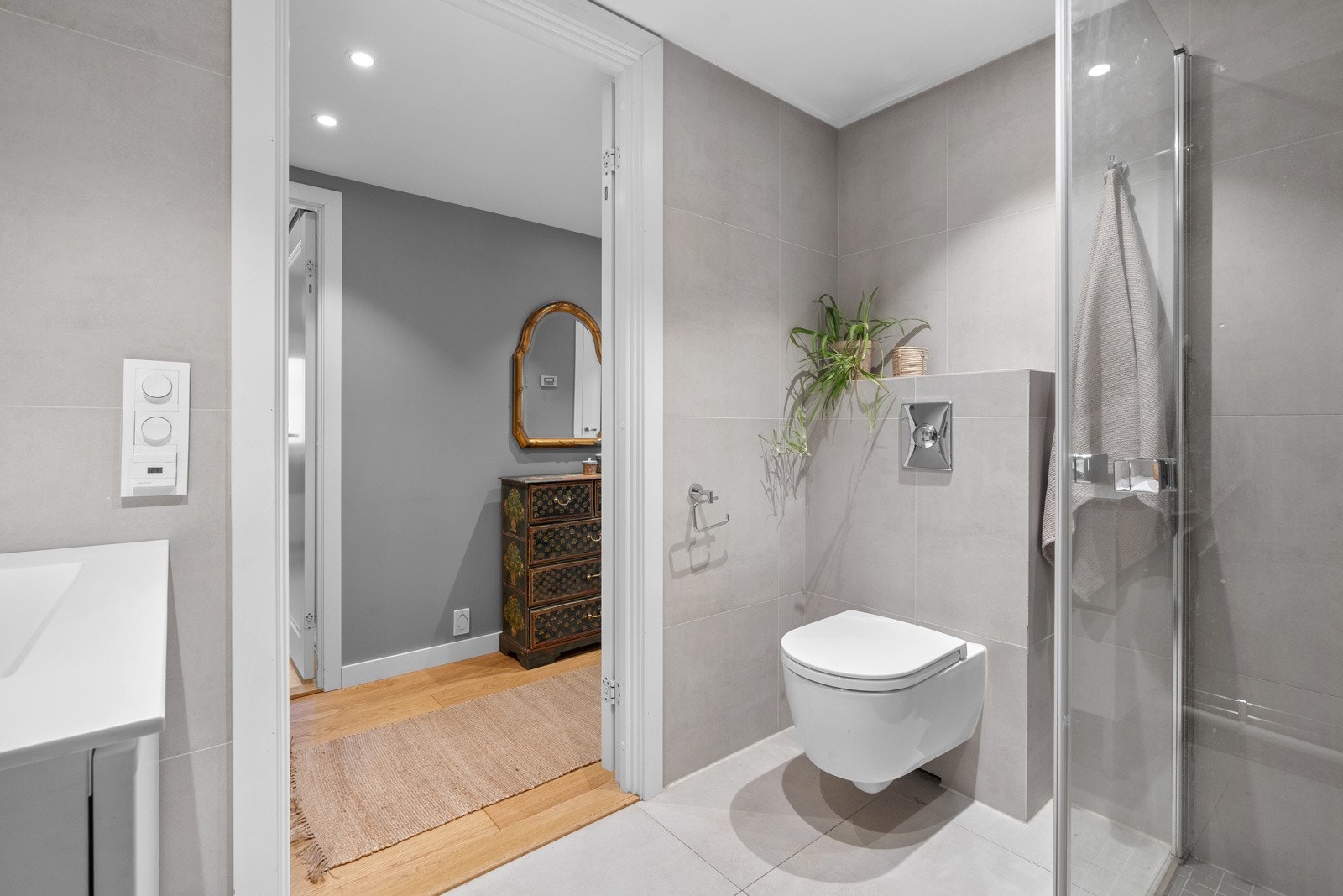 Romslig bad med varme i gulv og downlights i himling. Et godt sted å starte dagen! Badet er utstyrt med vegghengt toalett, dusjhjørne med svingdører og heldekkende servant med skuffer for oppbevaring. Galleribilde