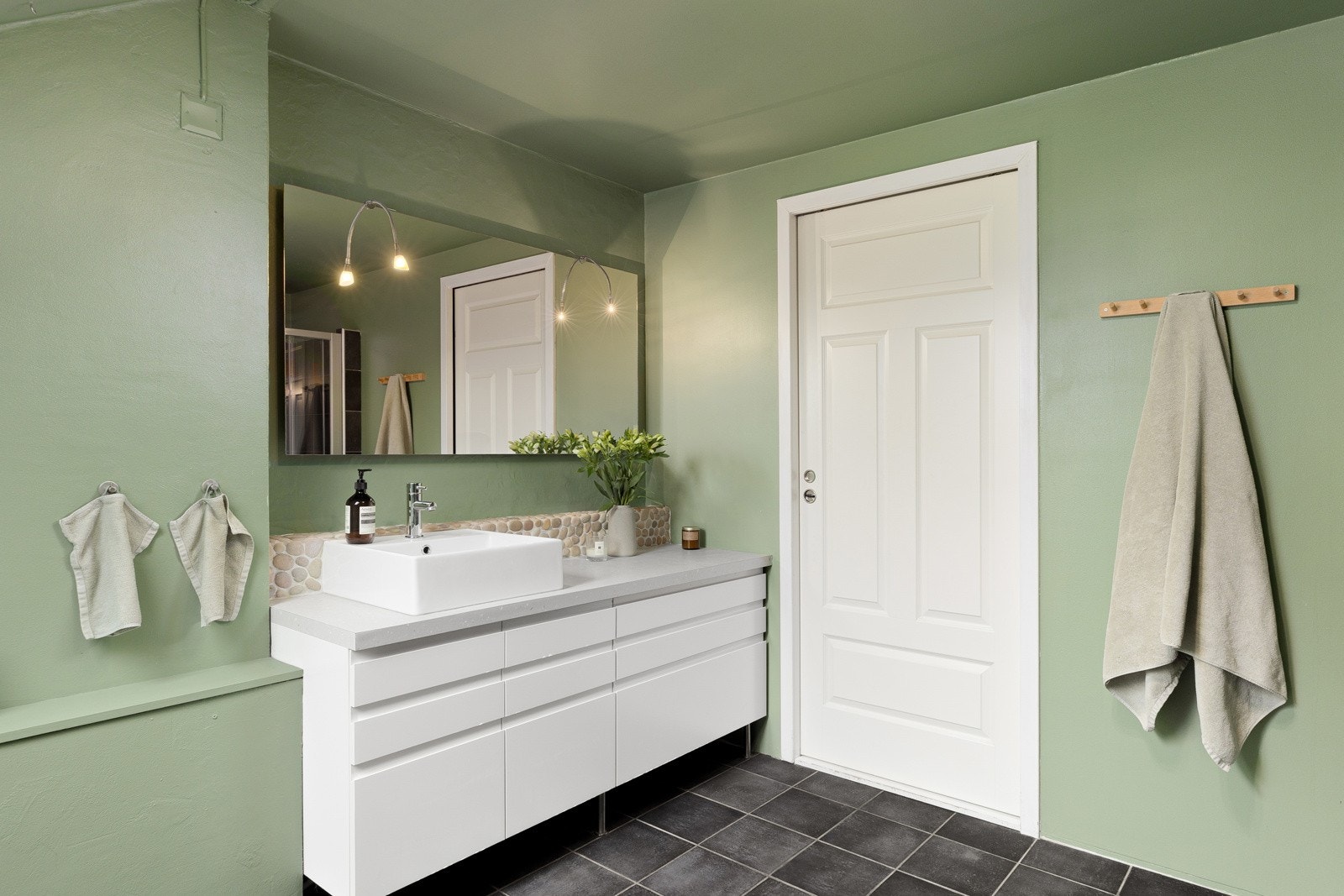 Veggfast toalett, servant med belysning, samt benkeskap med glatte fronter, er med på å heve standarden på dette flotte badet. Galleribilde