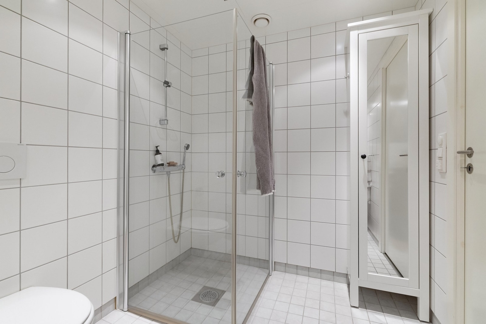 Dusjhjørne med innfellbare glassdører og dusjarmatur tilkoblet veggmontert hånddusj Galleribilde