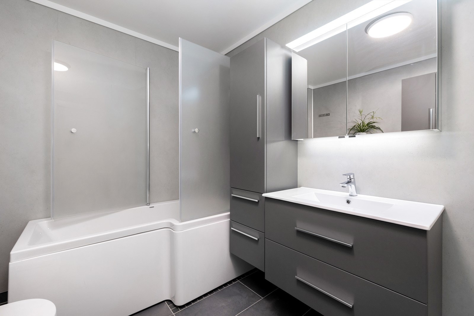 Badekar med dusjløsning, opplegg for vaskemaskin og god plass til toalettsaker i innredningen. Pen servant og godt med lys. Galleribilde