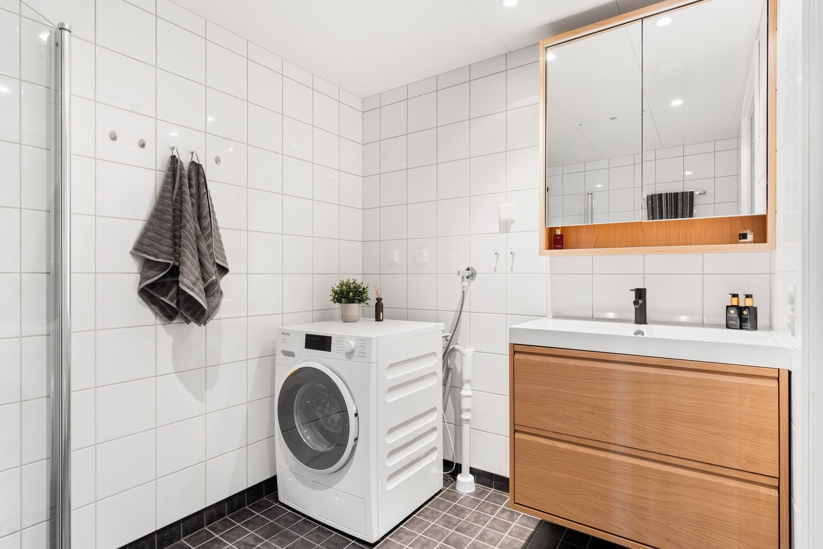 Innredningen består av et nytt servant- og speilskap med lys. Videre er det vegghengt toalett, nedsenket dusjhjørne med innfellbare
glassdører og dusjarmatur tilkoblet hånddusj og regndusj. Galleribilde