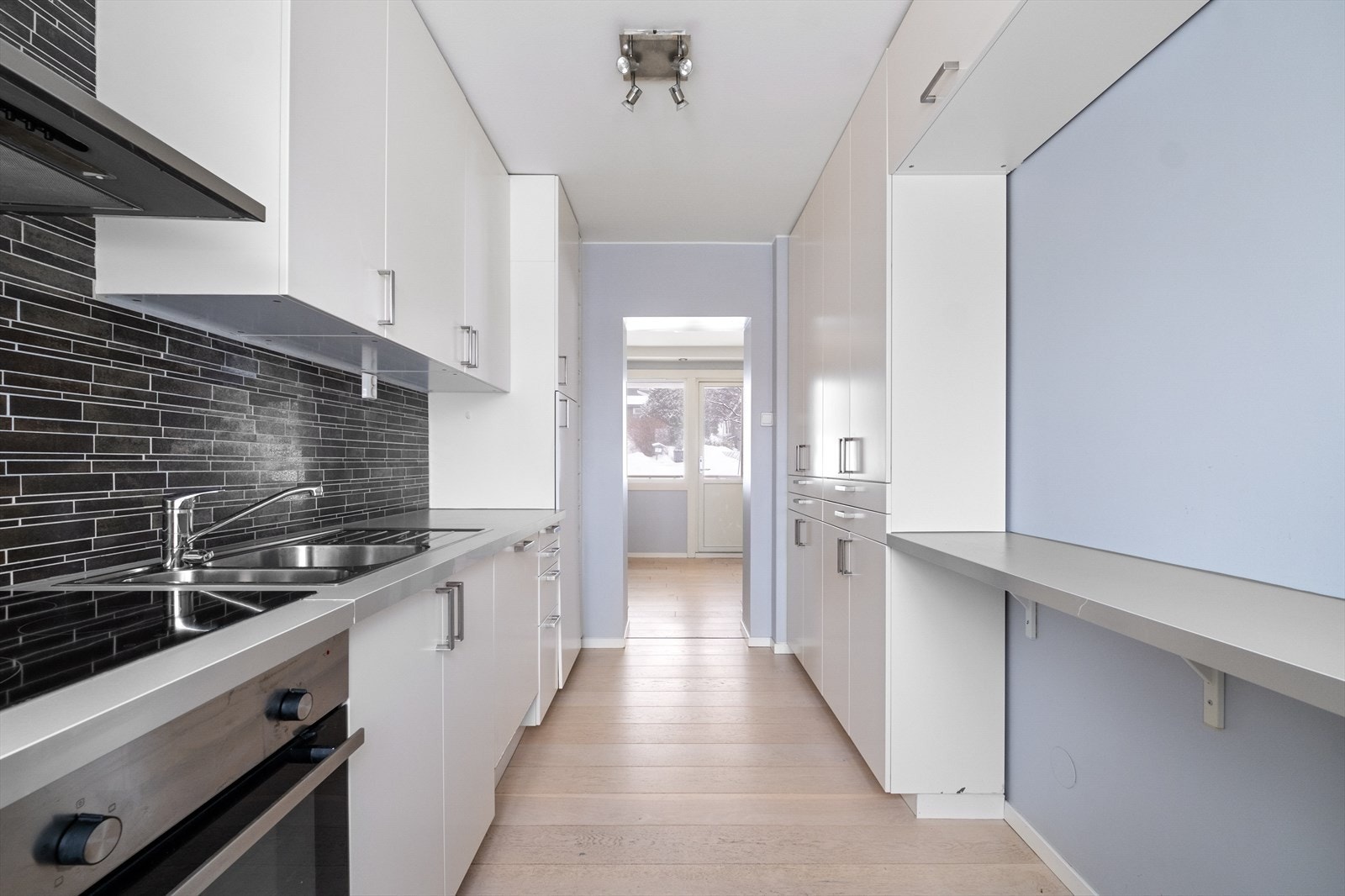 - Det er kjøkkeninnredning med glatte fronter og laminat benkeplate med nedfelt vask- og skyllekum. platetopp, Stekeovn. Kjøkkenventilator med avtrekk ut - Galleribilde