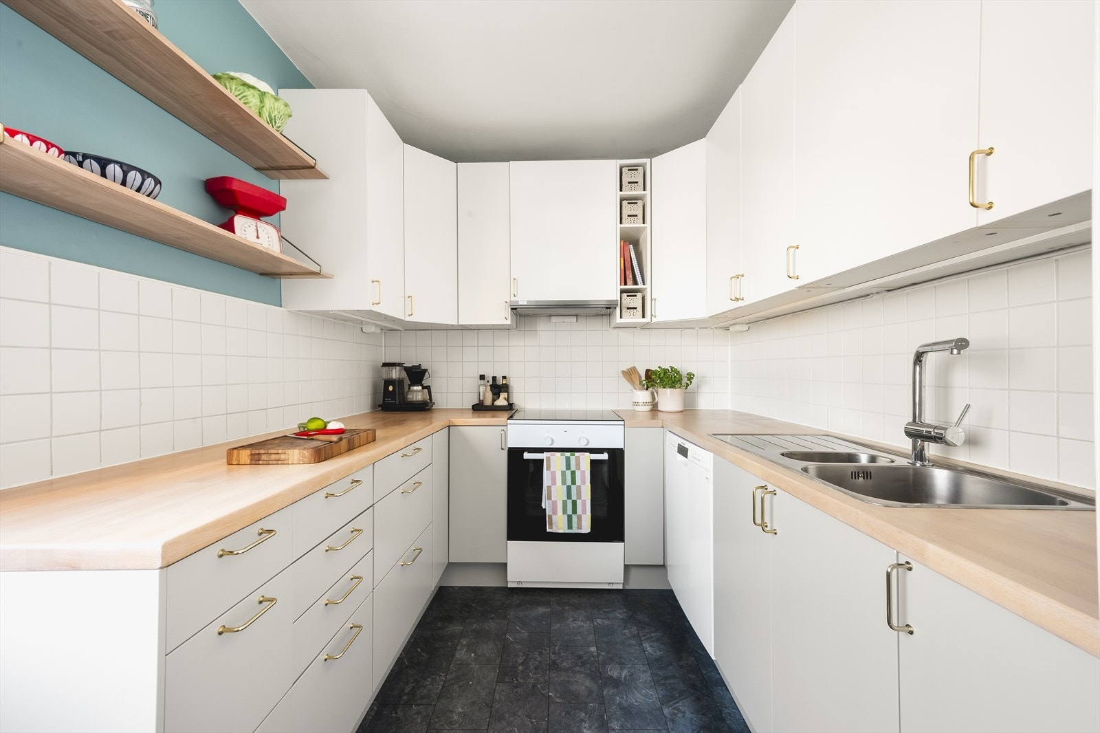 Moderne innredning med glatte, lyse fronter, fliser på vegg over kjøkkenbenk og heltre benkeplate. Galleribilde