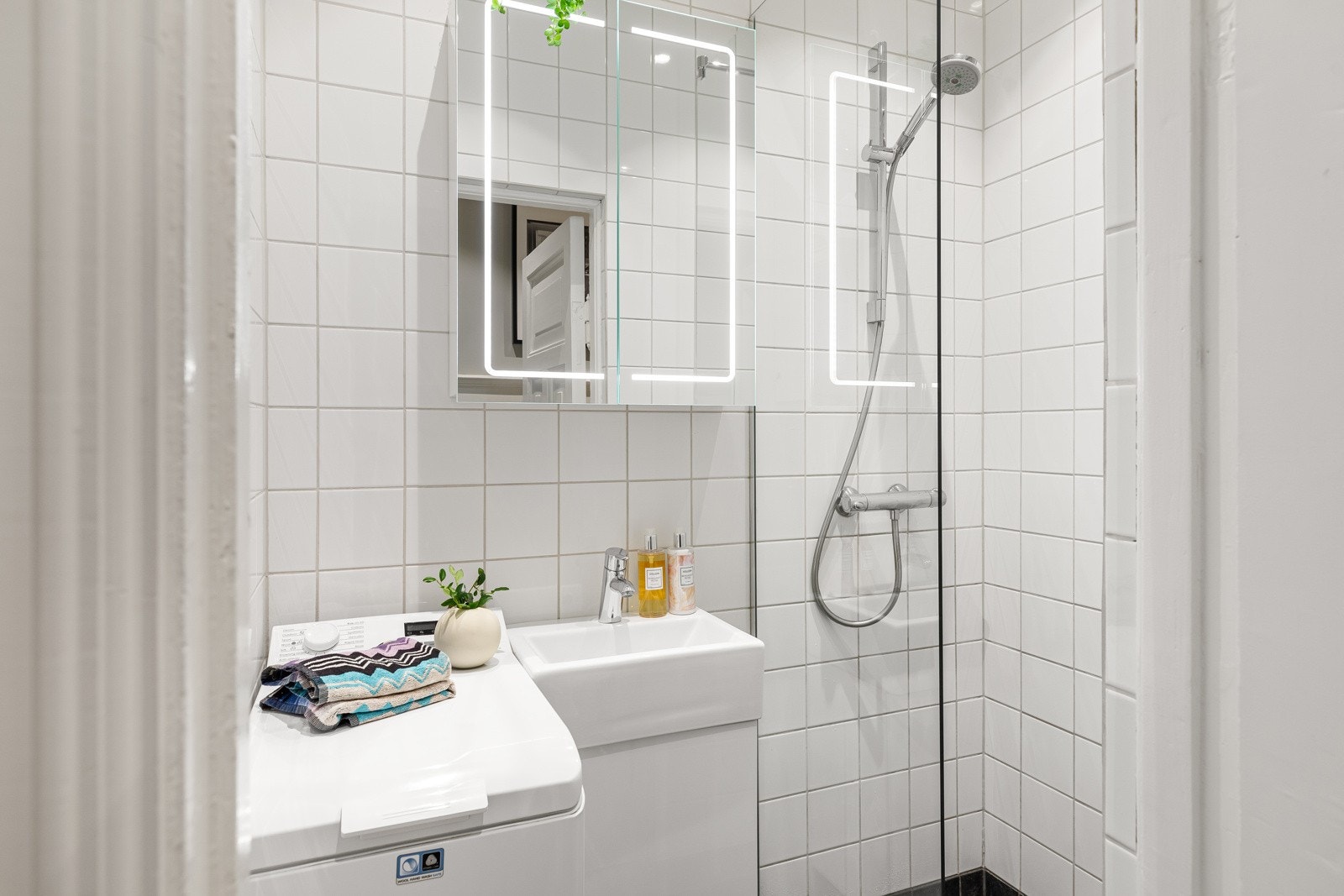 Flislagt dusjbad med varmekabler i gulv og downlights i himling. Videre har badet dusj rett på flis, veggmontert servantskap og speilskap med belysning. Det opplyses i forrige salgsoppgave at badet ble pusset opp i 2008 Galleribilde