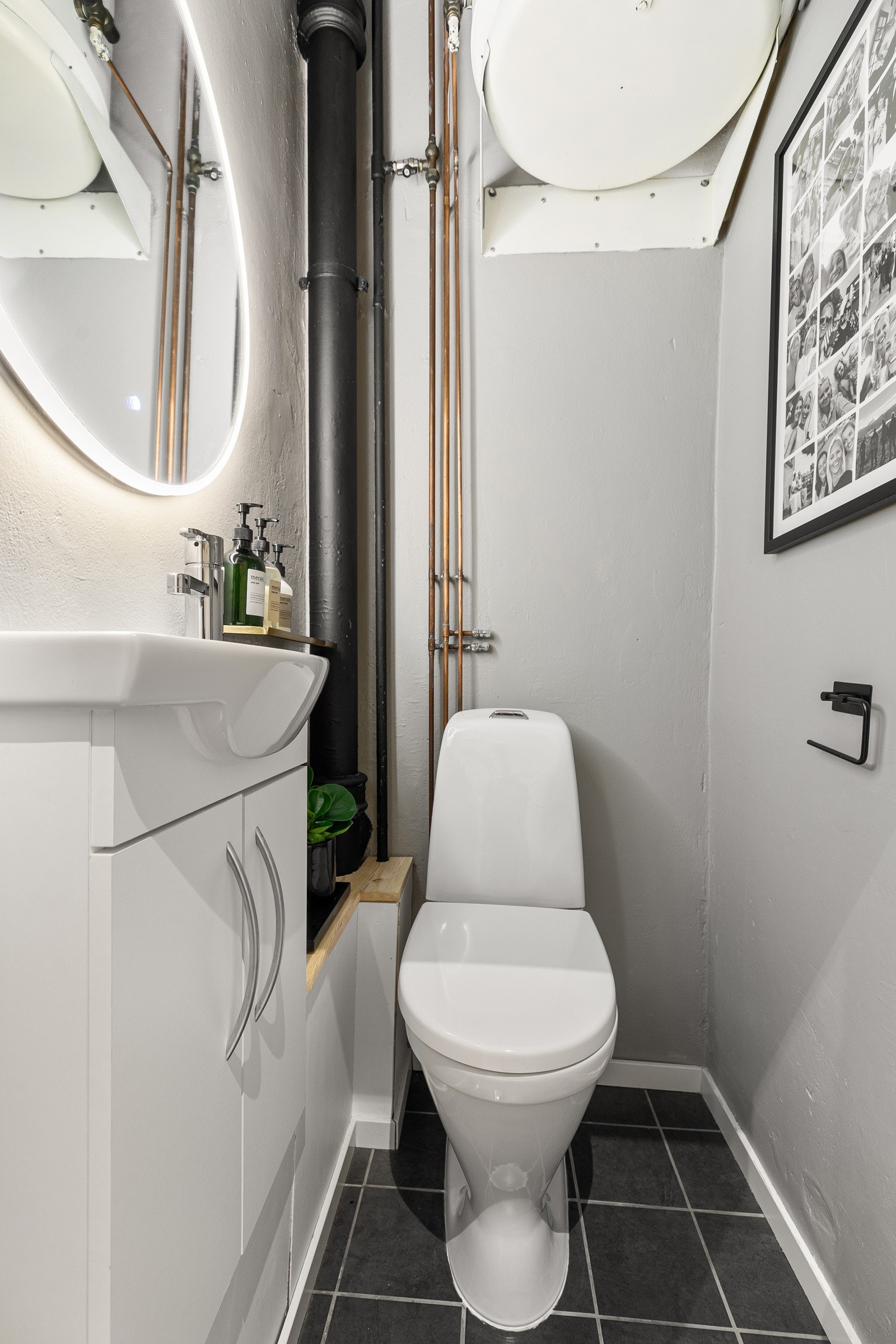 Delvis flislagt toalettrom med varmekabler i gulv. Rommet har veggmontert servantskap med heldekkende vask med ett-greps armatur i krom og gulvstående klosett. Varmtvannstank plassert i himling Galleribilde