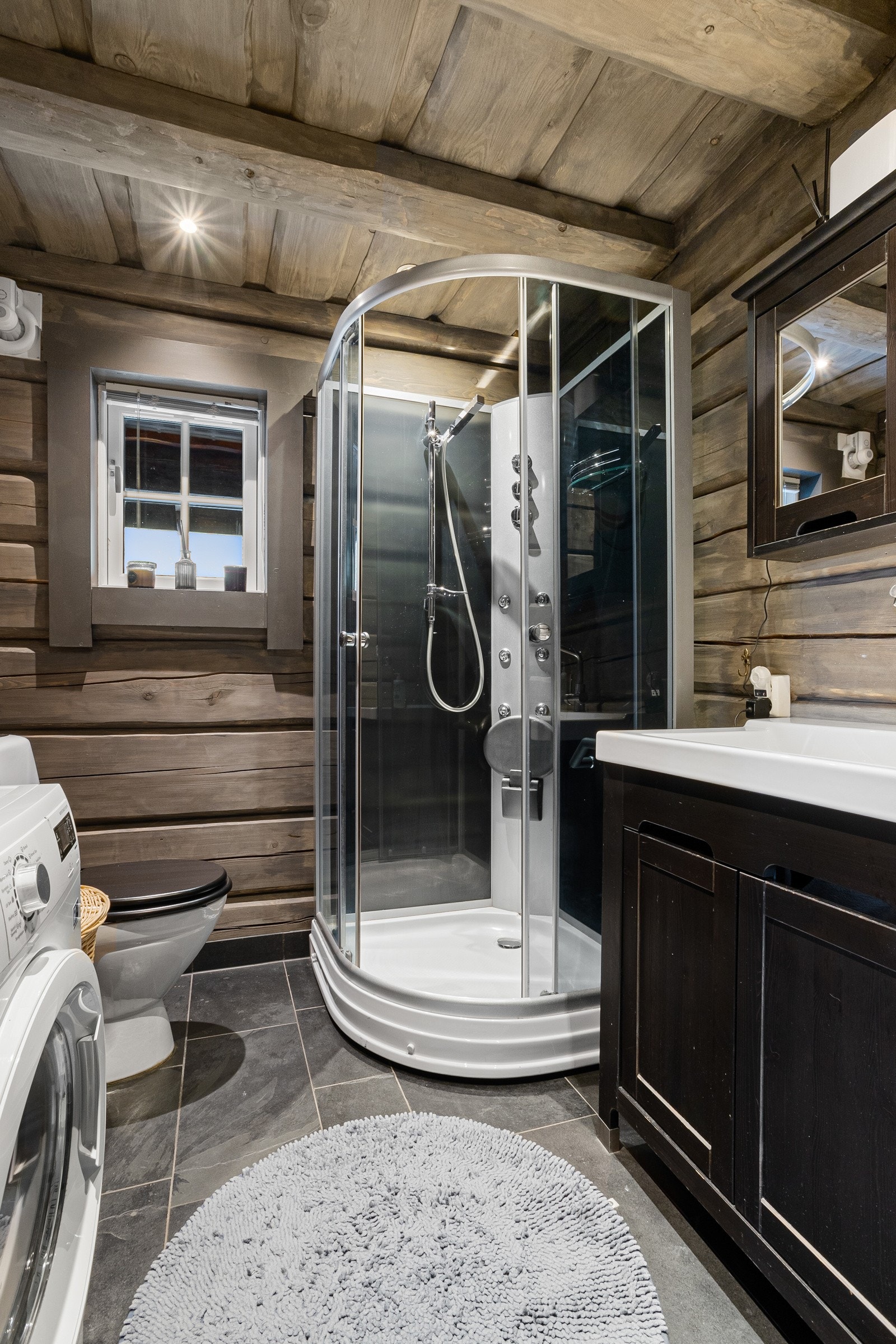 Baderom II er innredet med baderomsinnredning med servant, dusjkabinett, toalett og opplegg til vaskemaskin Galleribilde