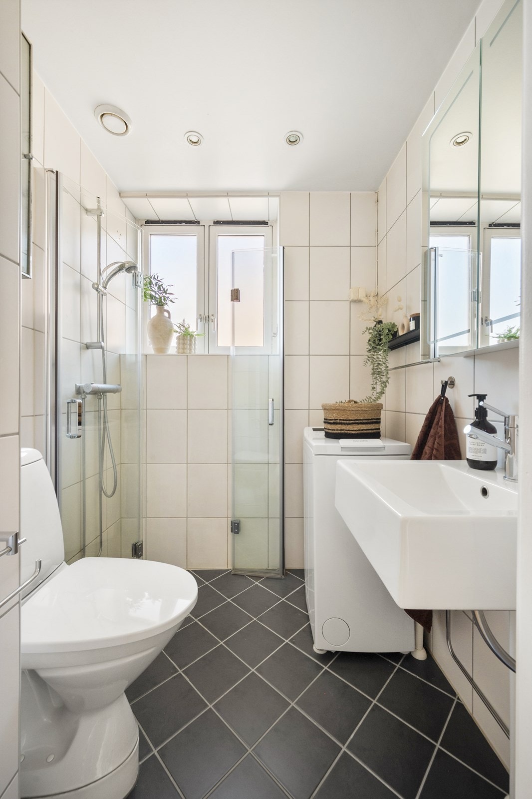 Badet er innredet med toalett, vegghengt servant, speilskap m/lys og dusjhjørne med svingbare glassdører. Galleribilde