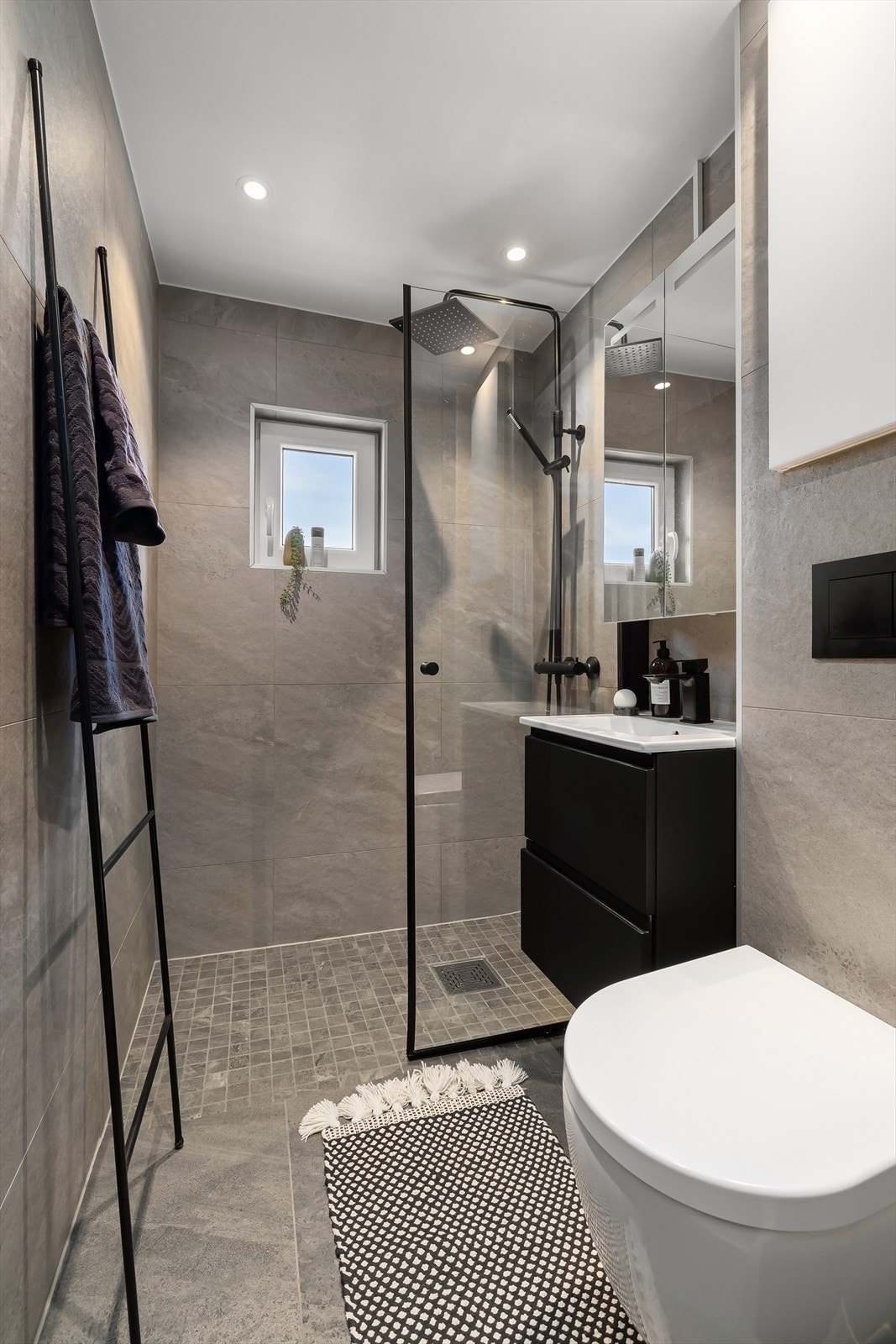 Speilskap med belysning og stikkontakter på vegg. Innebygget overskap i innkassing. Vegghengt toalett. Galleribilde