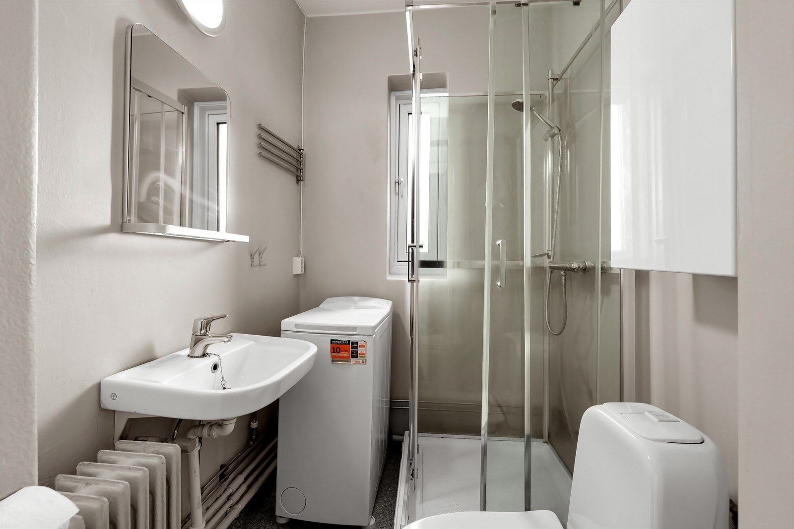 På badet er det en servant, toalett og dusjkabinett med glassdører/vegger Galleribilde