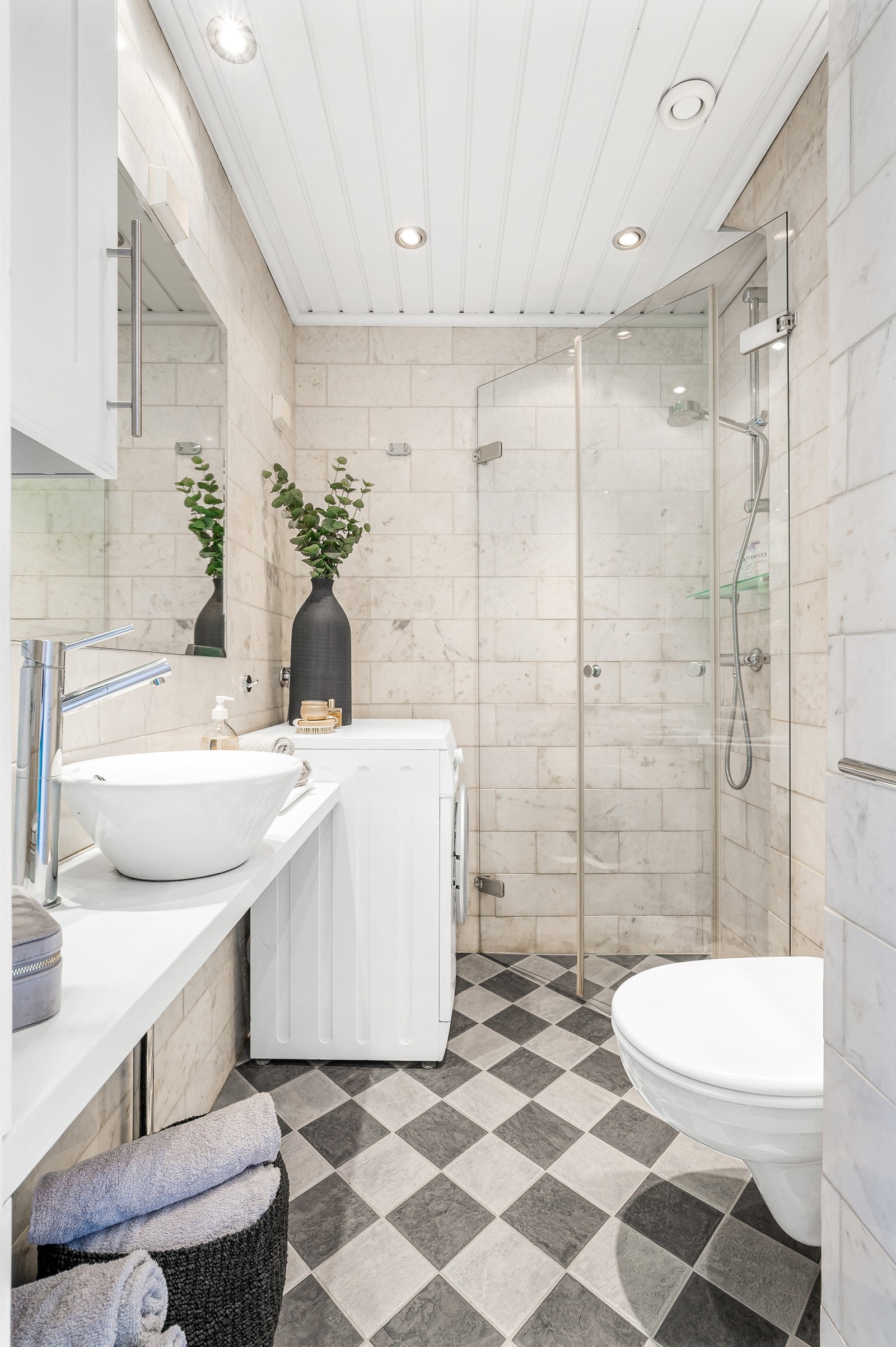 Badet er innredet med benkeplate av tre, overpåliggende servantskål, speil og overskap, dusjhjørne med innfellbare dører og vegghengt toalett. Galleribilde