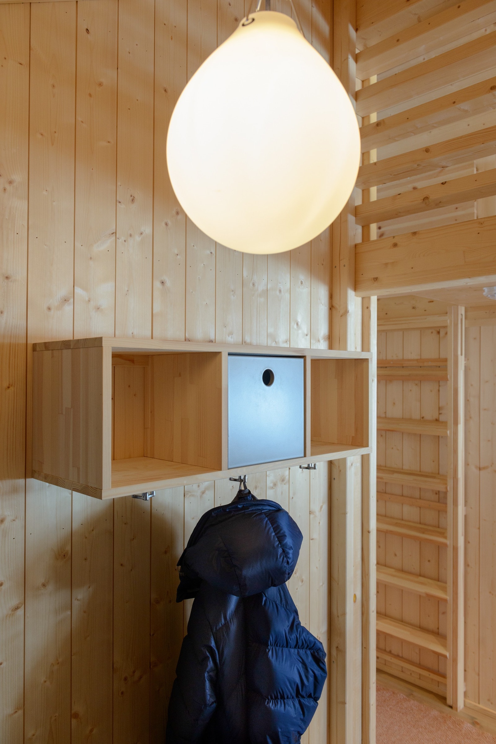 Praktiske og estetisk fine oppbevaringsløsninger i gangen. Oppe til høyre kan du se hemsen. Lampa fra Louis Poulsen følger hytta. Galleribilde