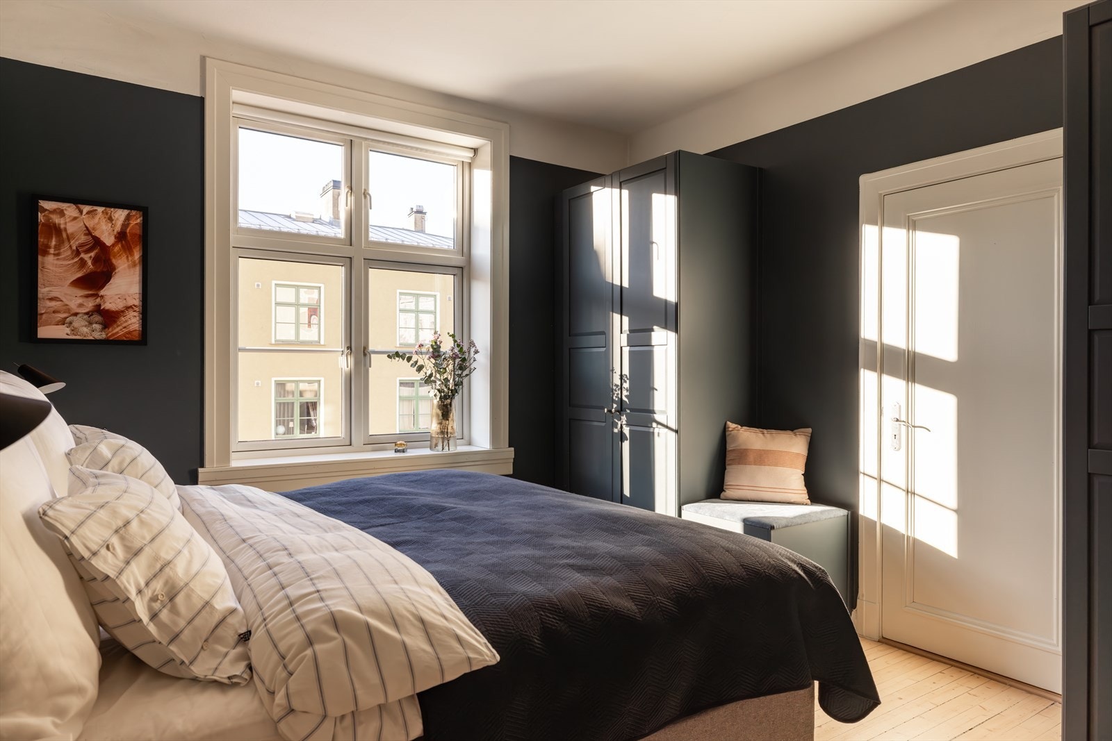 Et lunt soverom med plass til dobbeltseng, nattbord og garderobeskap Galleribilde