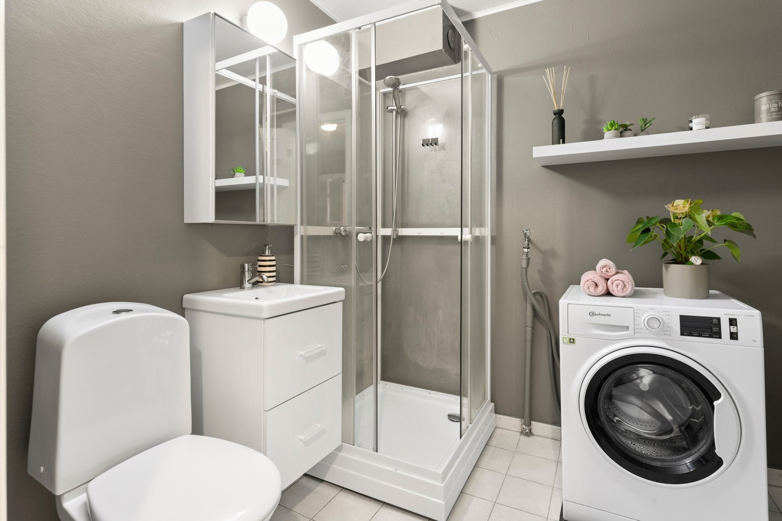 Badet er et praktisk og velholdt rom med flislagt gulv og vegger malt med våtromstapet. Galleribilde