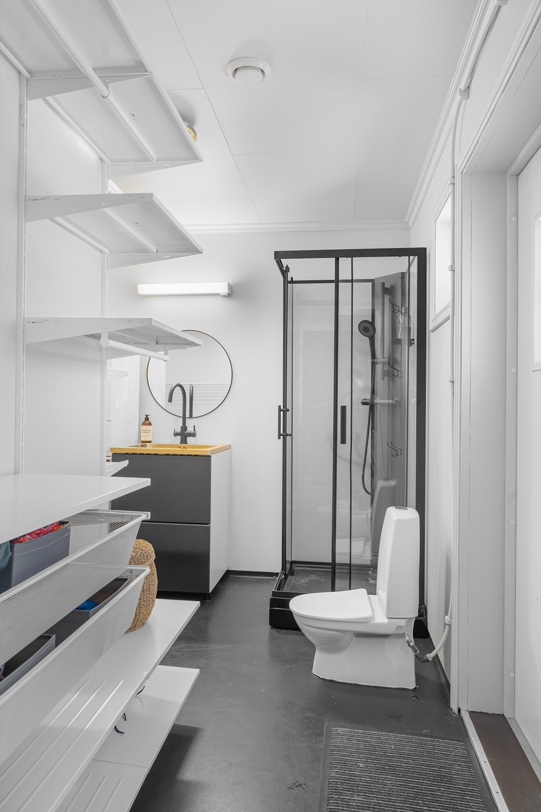 Praktisk bad/vaskerom i 1. etasje med adkomst både fra gangen og utenifra. Her er det god oppbevaringsplass i åpen løsning med hyller, kurver og oppheng. Galleribilde