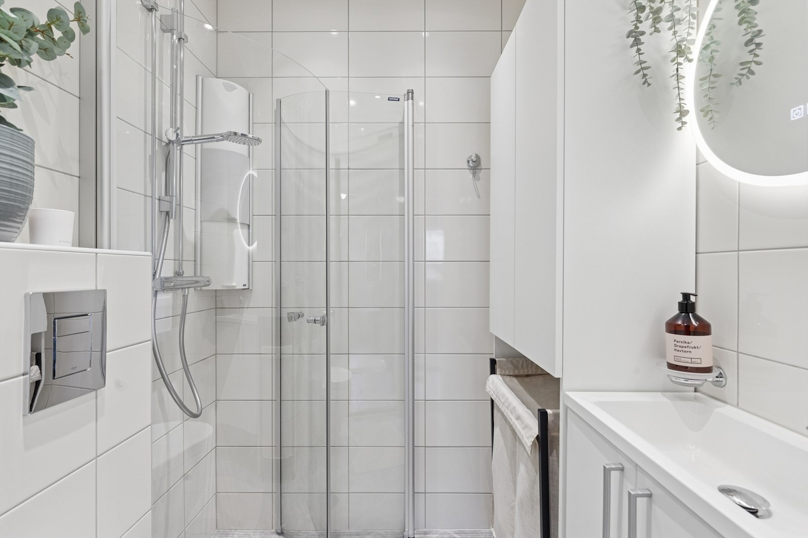 Badet er innredet med heldekkende servant på underskap med folierte fronter, speil med integrert lysarmatur og varme, og veggmontert klosett. Galleribilde