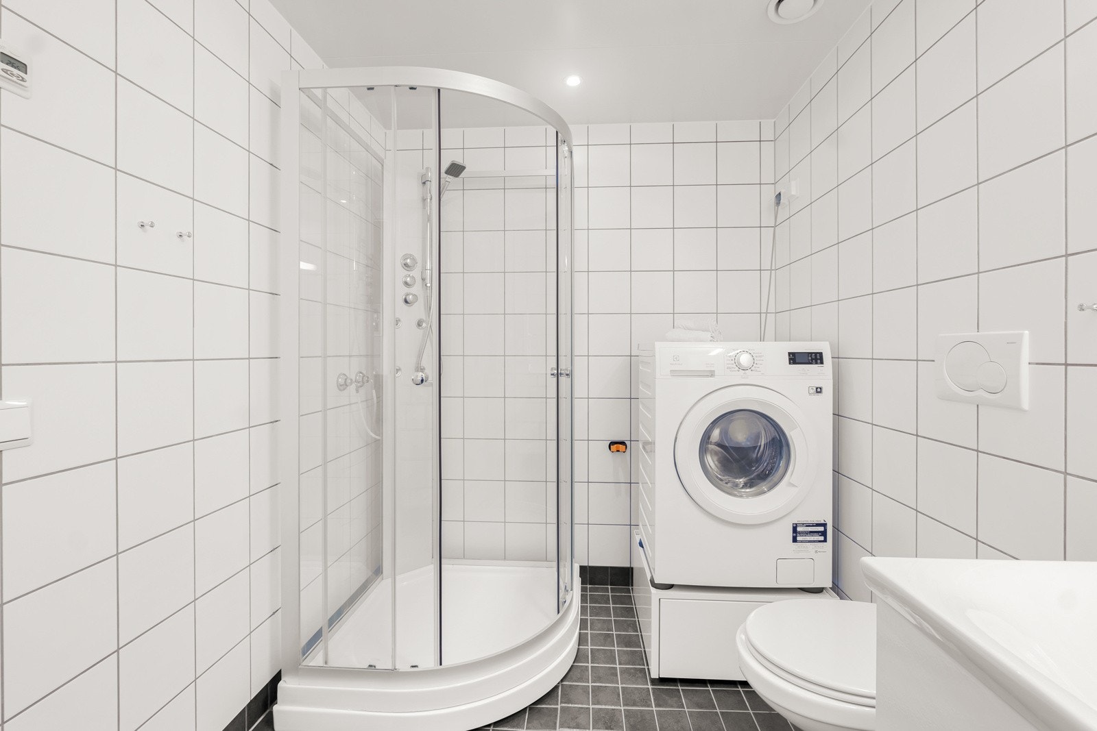 Praktisk dusjkabinett samt plass til både vaskemaskin og tørketrommel for en funksjonell og fleksibel baderomsløsning. Galleribilde