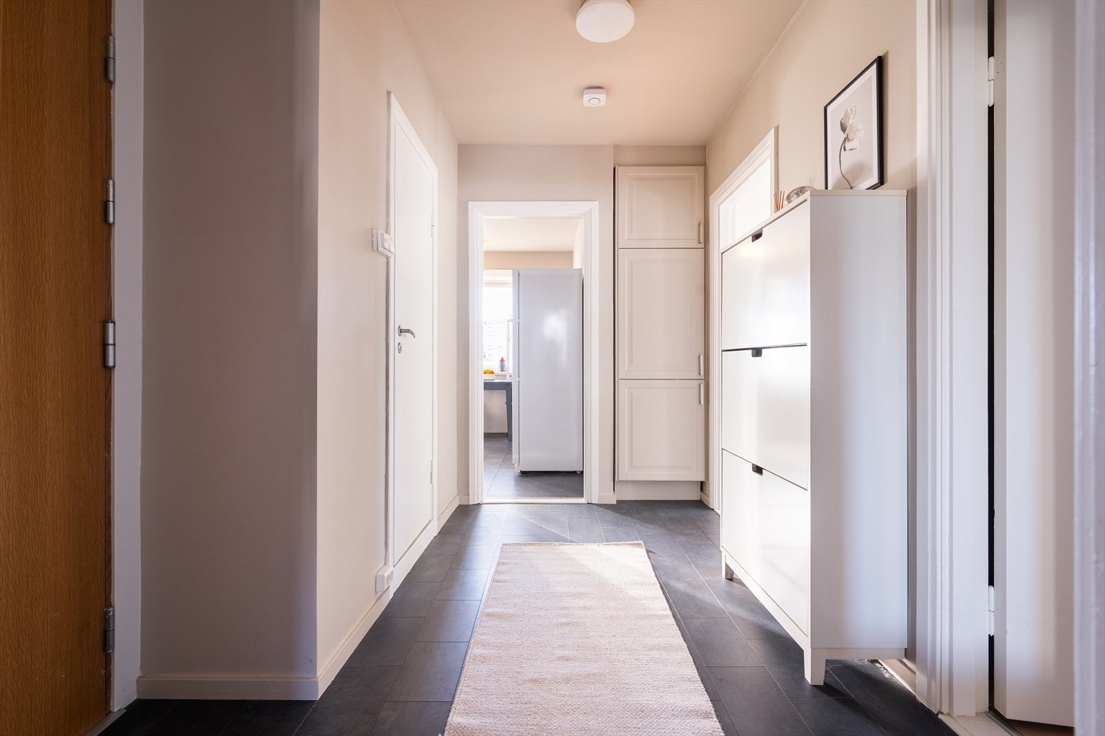 Lys og innbydende entré med slitesterke laminat med flismønster på gulvet. Galleribilde