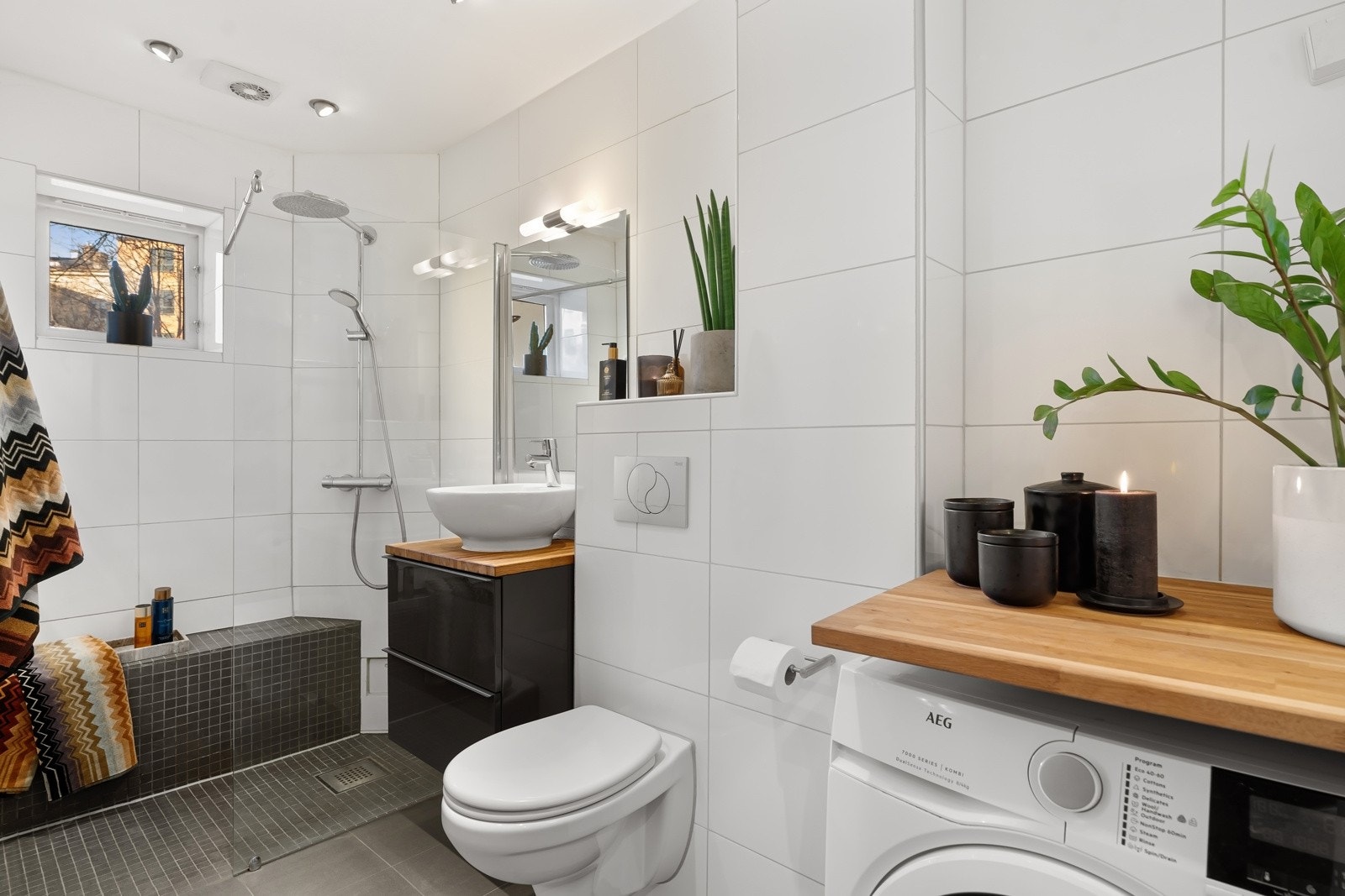 Badet er utstyrt med veggmontert toalett, en dusjsone med glassvegg og opplegg for vaskemaskin. Galleribilde