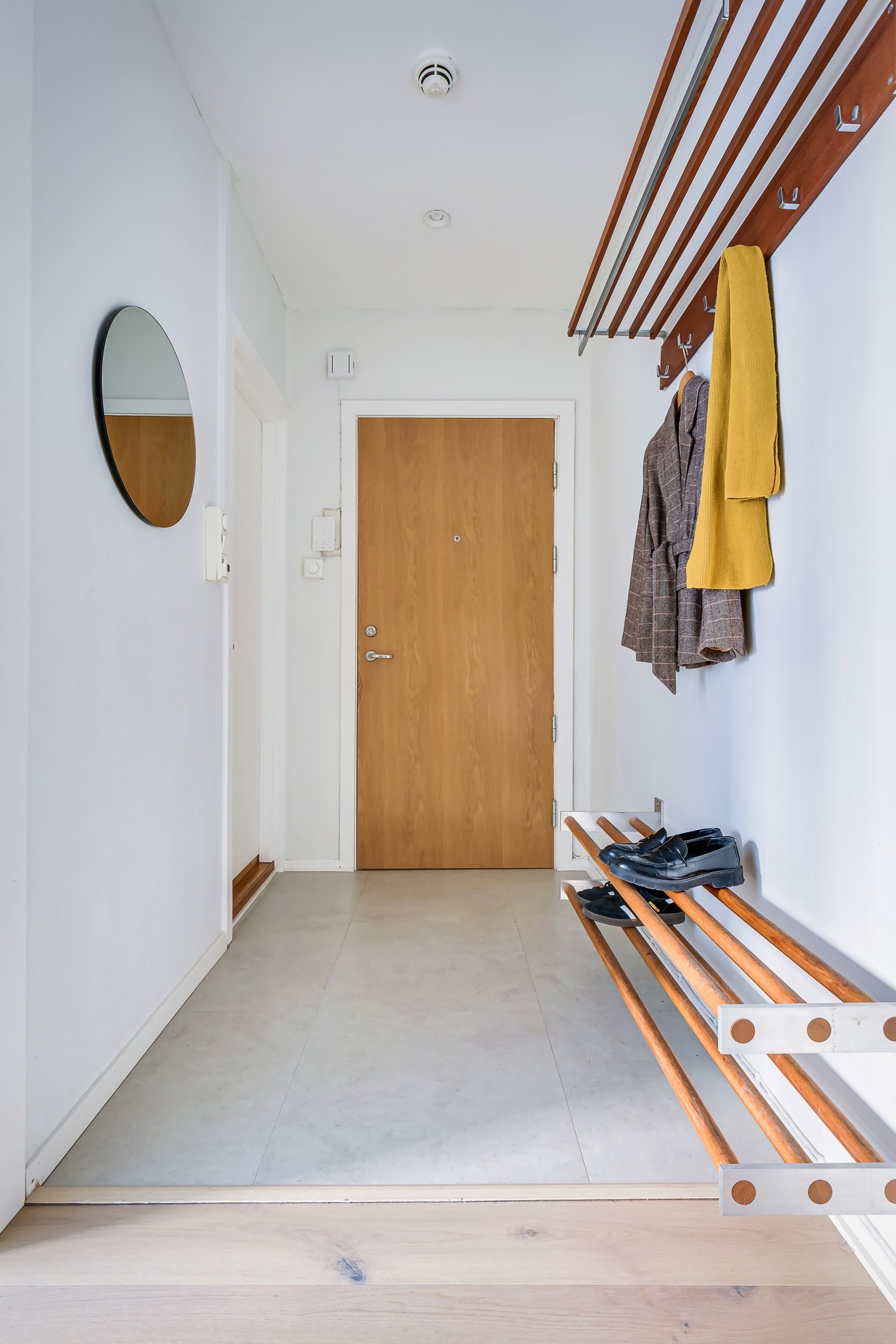 Du kommer inn i en lys og praktisk entré. Montert porttelefon på vegg og sikringsskap med automatsikringer i felles trapperom. Galleribilde