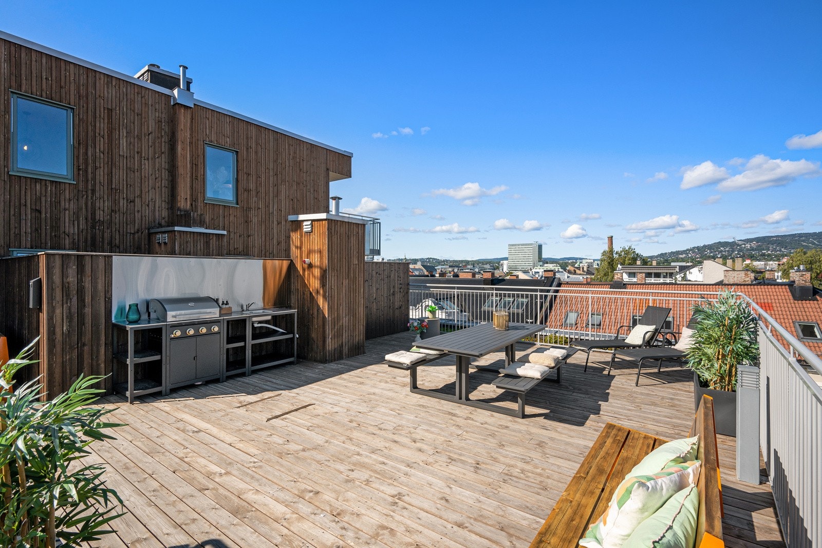 Takterrassen er pent innredet med sittegrupper, grill og grønne vekster. Galleribilde