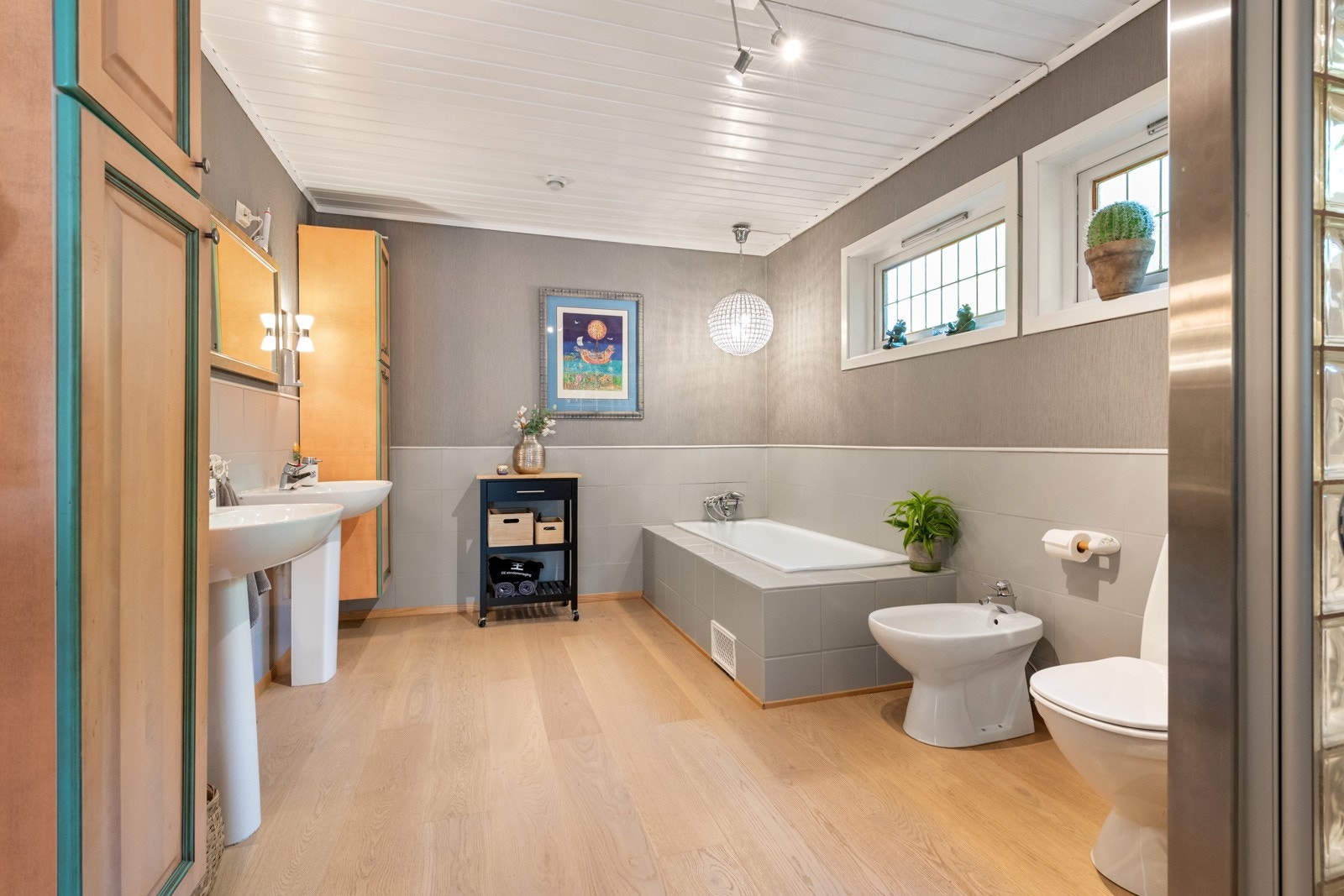 Romslig bad med både badekar og dusjnisje, 2 frittstående servanter og med skapmoduler Galleribilde