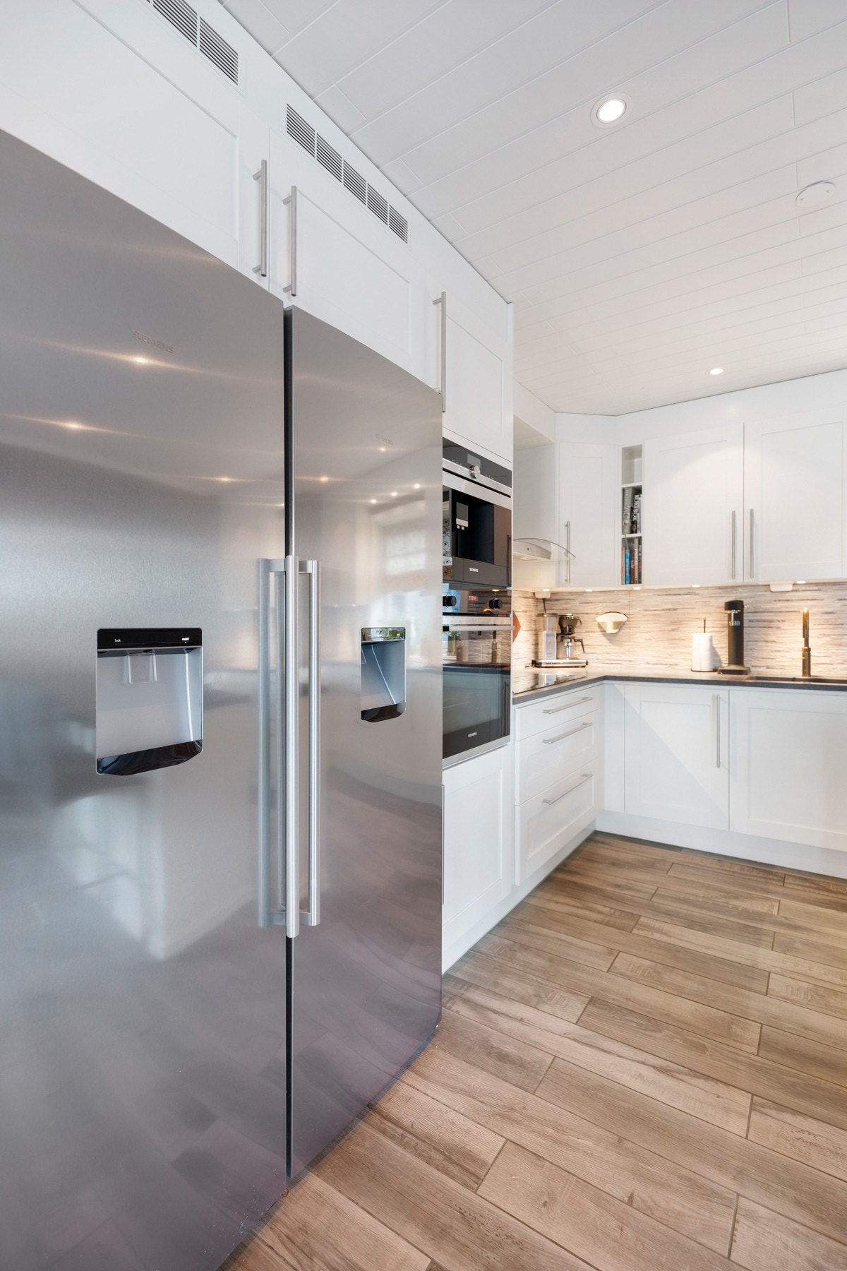 Integrerte hvitevarer; stekeovn, platetopp, oppvaskmaskin, kaffemaskin og vinskap. Galleribilde