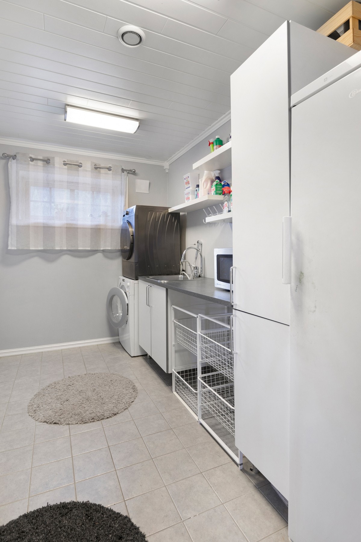 Separat vaskerom med flis på gulv og tapet på vegger. Rommet har egen utgang og er videre utstyrt med innredning, utslagsvask og opplegg for vaskemaskin/tørketrommel. Galleribilde