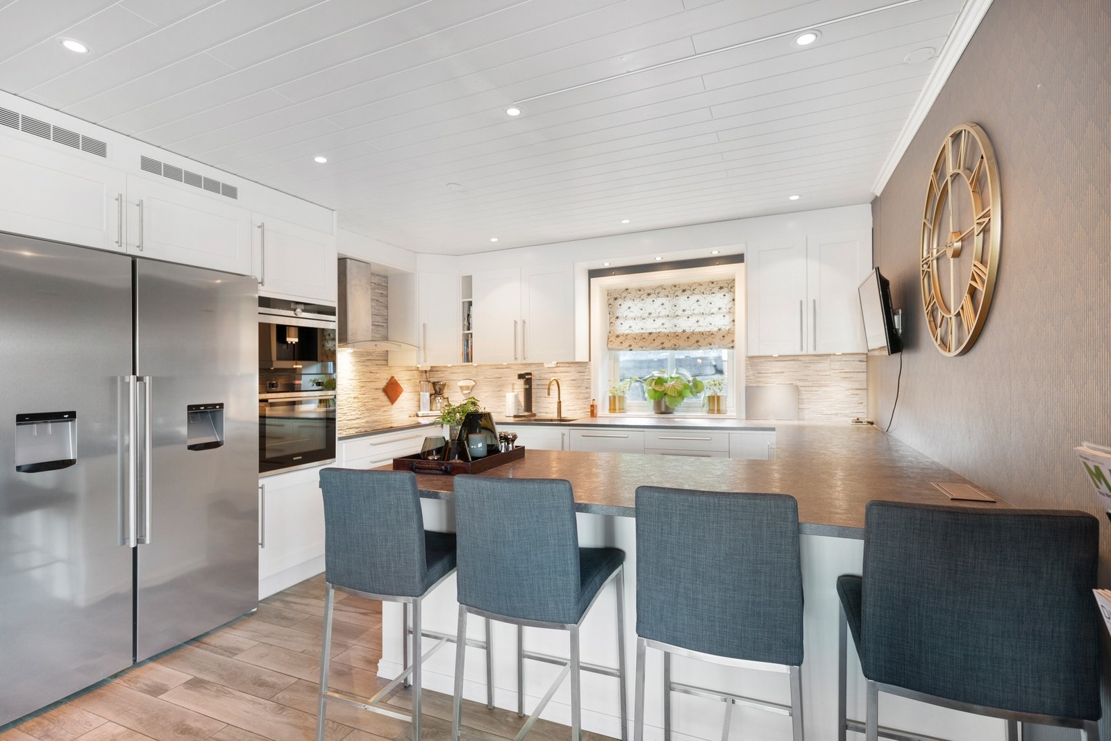 Innredningen er utvidet og ombygget i senere tid og inneholder laminat benkeplate med flis/skifer mot overskap, ventilator, utsparring for dobbelt amerikansk kjøleskap, Quooker i underskap, samt barløsning mot spisestue med sitteplasser. Galleribilde