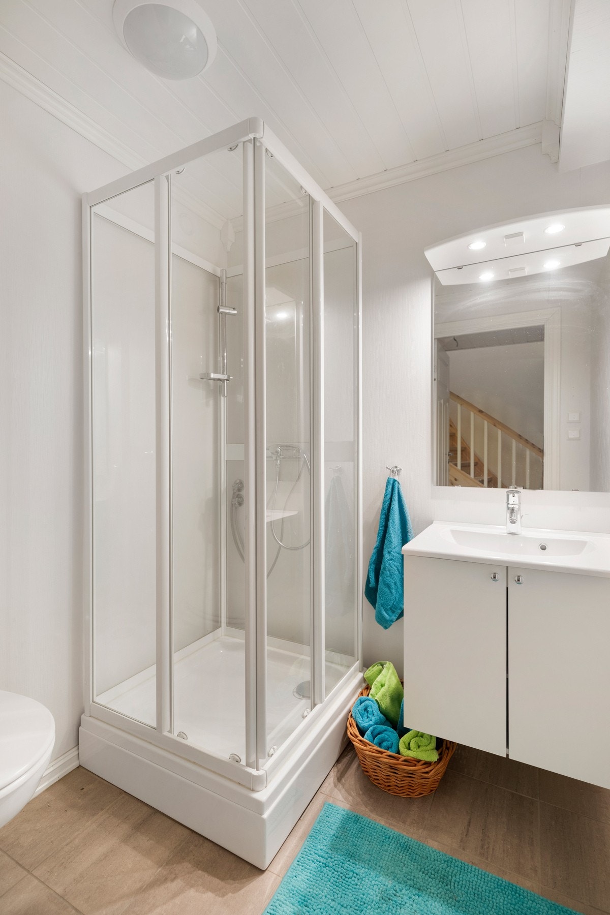 Bad med flislagt gulv, dusjkabinett, toalett og baderomsinnredning. Galleribilde