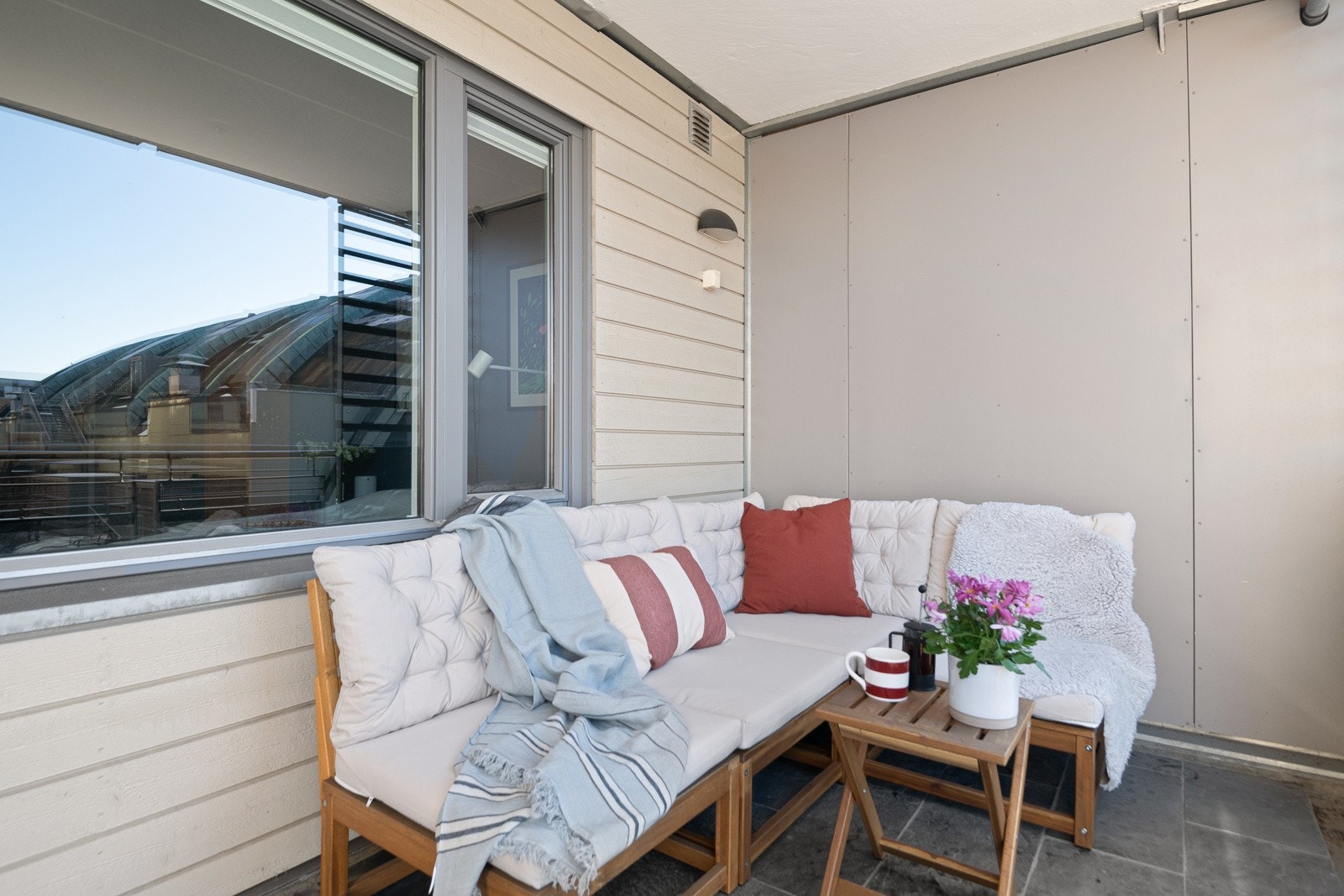 Balkongen er overbygget, har fliser på gulv og rekkverk med glassfelt. Det er også montert utebelysning og stikkontakt. Galleribilde