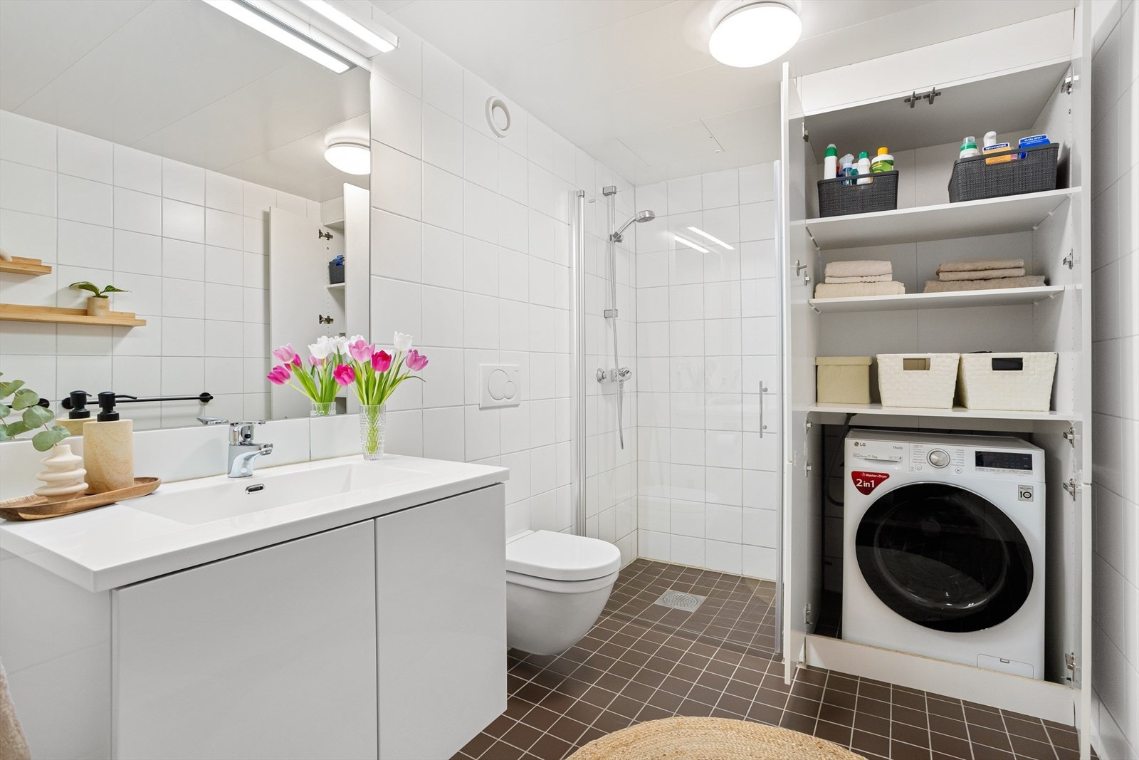 Baderommet er innredet med vegghengt klosett, servant med innredning, innfelt speil og dusjhjørne med svingbar glassdør. Opplegg for vaskemaskin i praktisk skap. Galleribilde