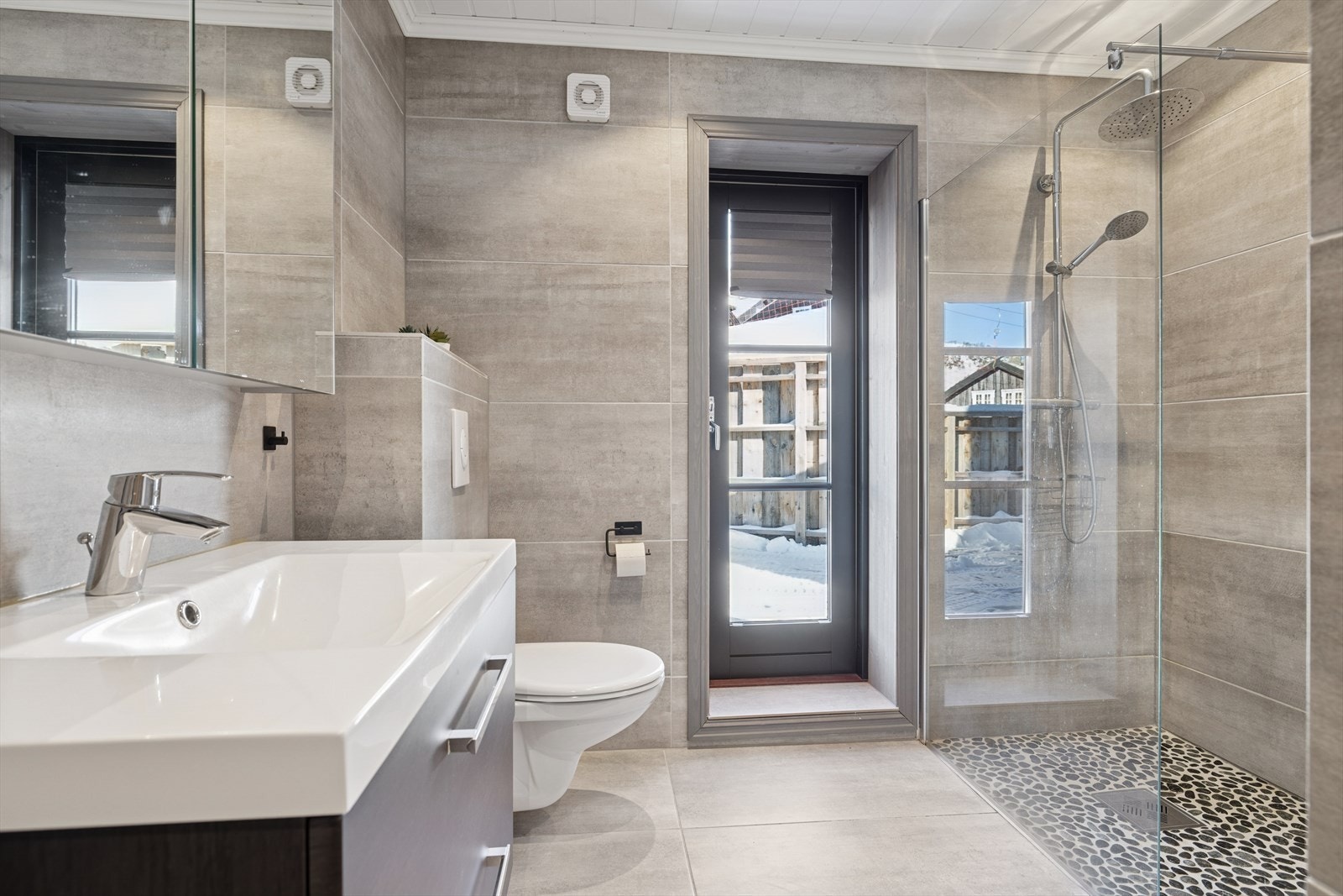 BaderomBadet i hovedetasjen er lekkert med fliser på gulv og vegg, inngang til badstue fra badet og utgang til terrasse og jacuzzi. Galleribilde