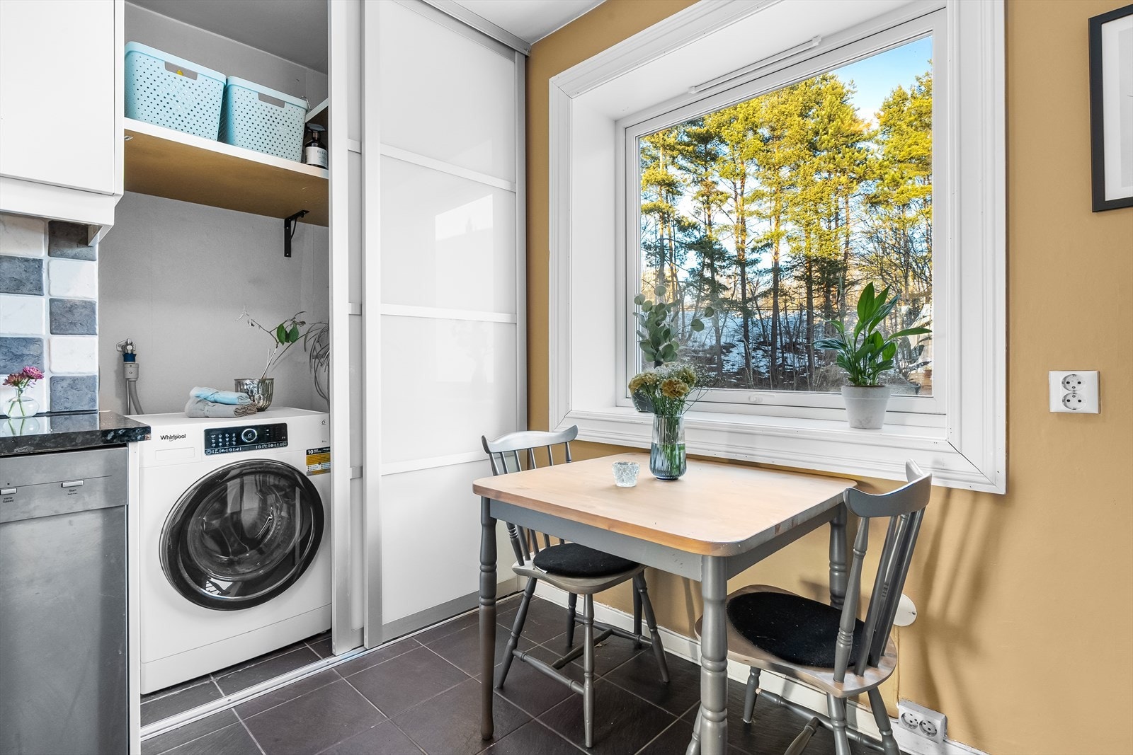 På kjøkkenet er det et praktisk skyvedørsskap med plass til vaskemaskin og oppbevaring av støvsuger m.m. Hyggelig med spiseplass også på kjøkkenet. Ekstra hyggelig er det å spise frokost her når det er frodig og grønt ute. Galleribilde