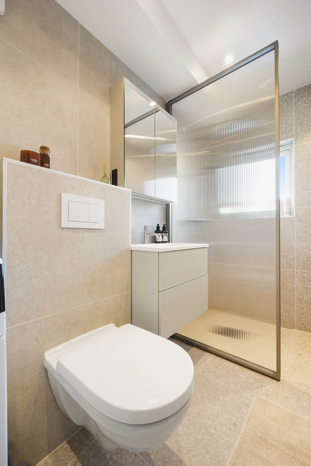 Badet består blant annet av romslig dusjhjørne, vegghengt toalett, servant med innredning og opplegg for vaskemaskin Galleribilde