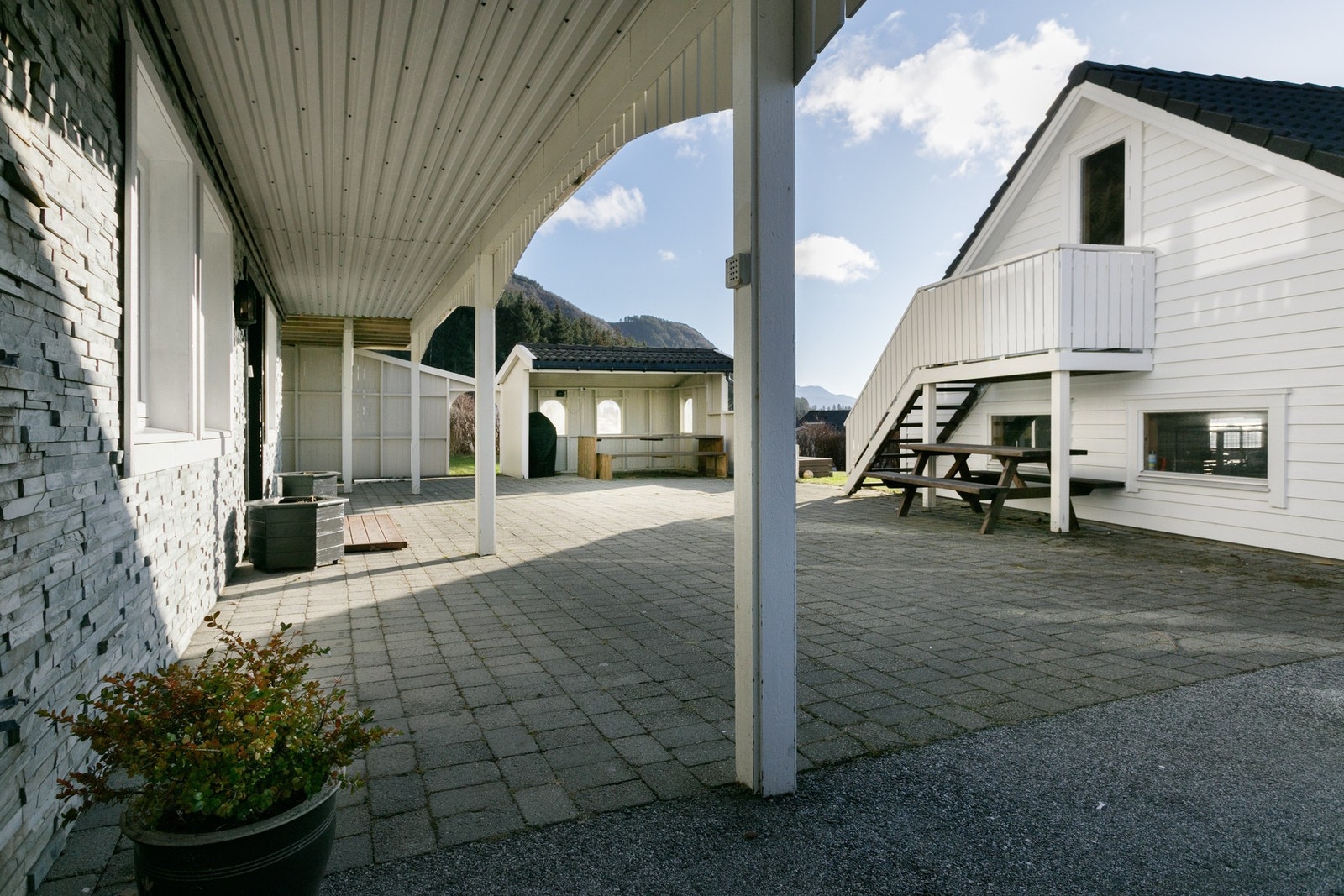 Tiltalende og oppusset inngangsparti med pen dekormur, overbygg, beleggningsstein og asfaltert innkjørsel. Galleribilde