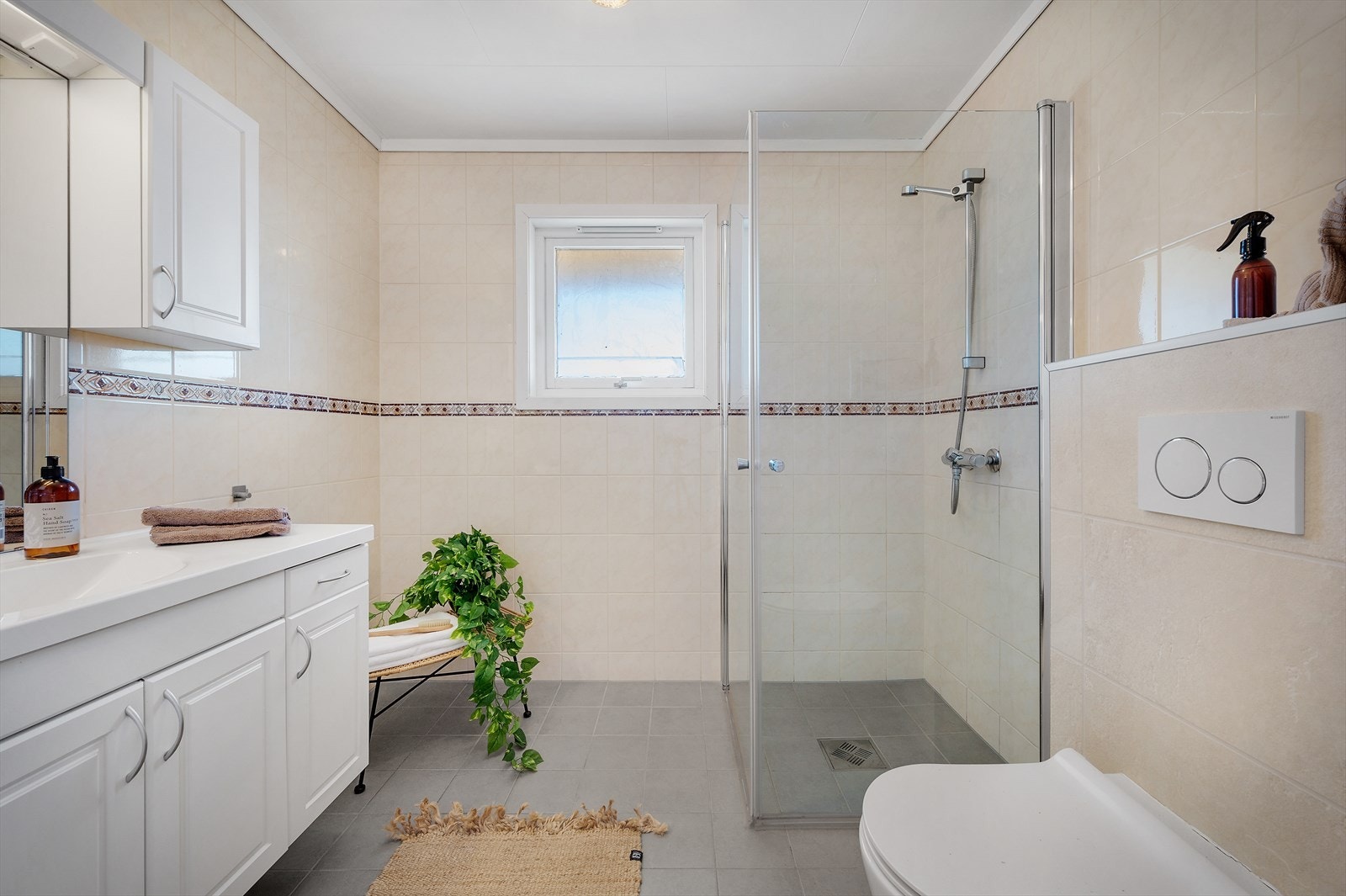 - Badet måler 4,9m² og er innredet med vegghengt toalett, servantmøbel og innfellbare dusjdører i glass - Galleribilde