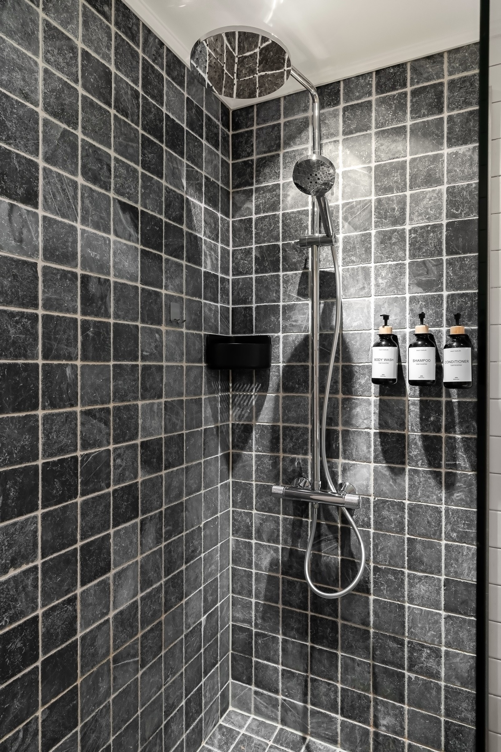 En romslig dusjnisje med regnfallsdusj og vegghengt oppbevaring. Galleribilde