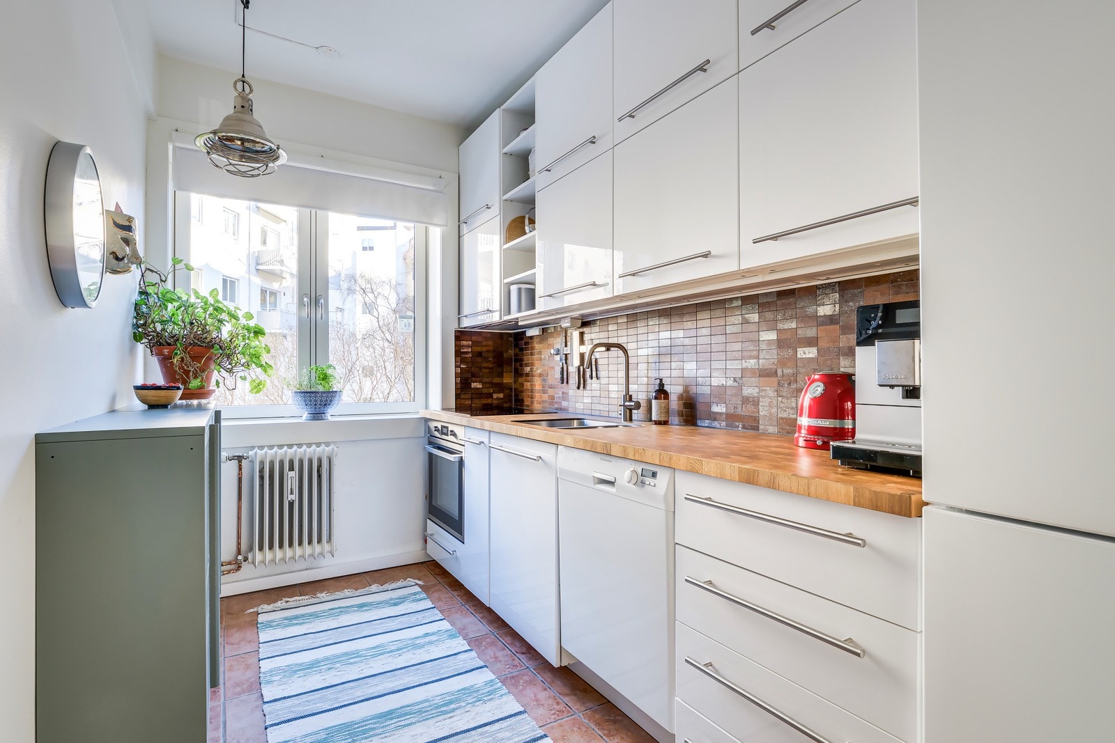 . Masse skap- og benkeplass i kjøkkeninnredning med hvite glatte fronter og ny heltre benkeplate. Ytterligere lagringsplass i vegghengte skap til venstre i bildet. Galleribilde