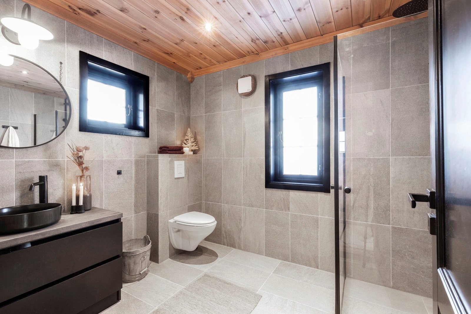 Hytta har 2 baderom. Her er baderom I i første etasje. Baderommet inneholder veggmontert toalett, dusjnisje og innredning med servant. Flislagte gulv- og veggflater. Varmekabler i gulv. Galleribilde