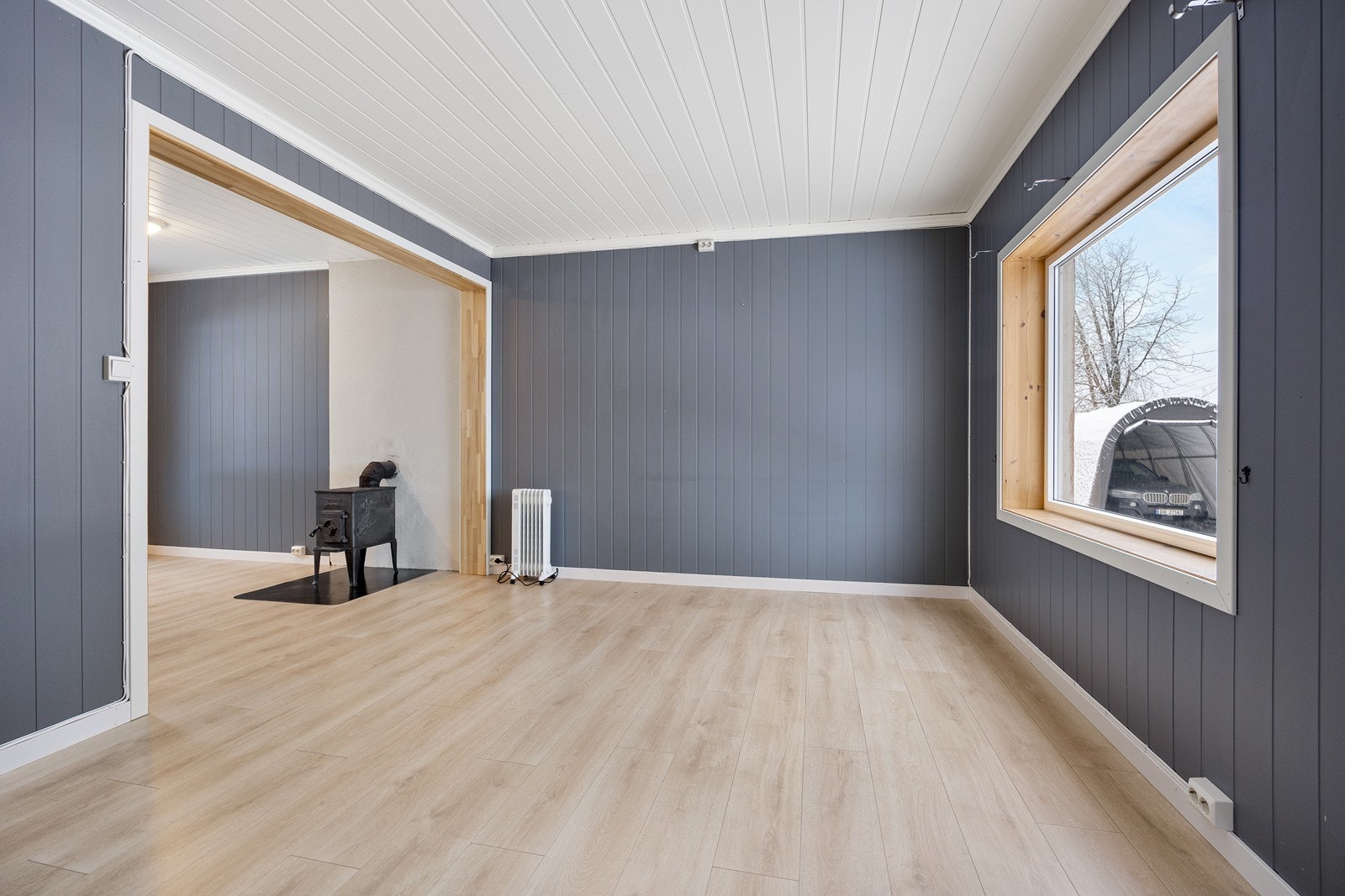 Stue og kjøkken har 1-stavs laminat på gulvet - og på veggene er det panelvegger i en tidsriktig blåtone. Galleribilde